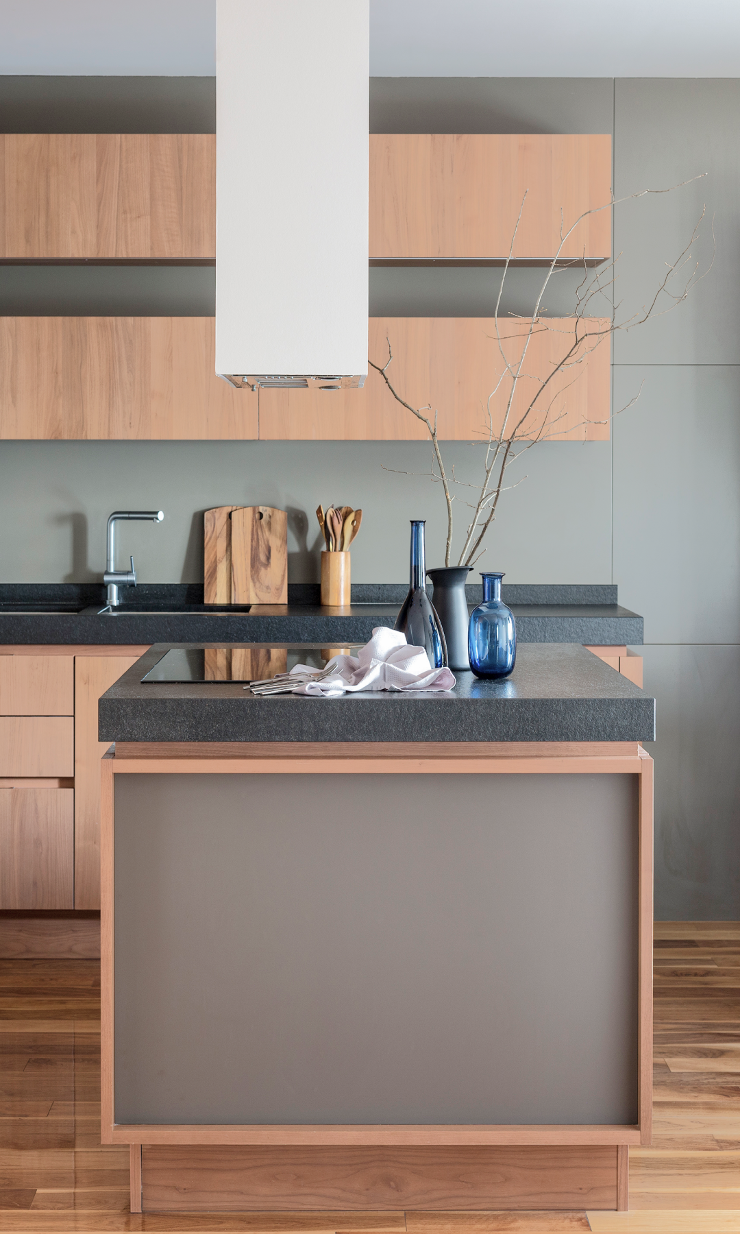 Modern kitchen with wooden cabinets, black countertops, island with decor, and steel faucet.