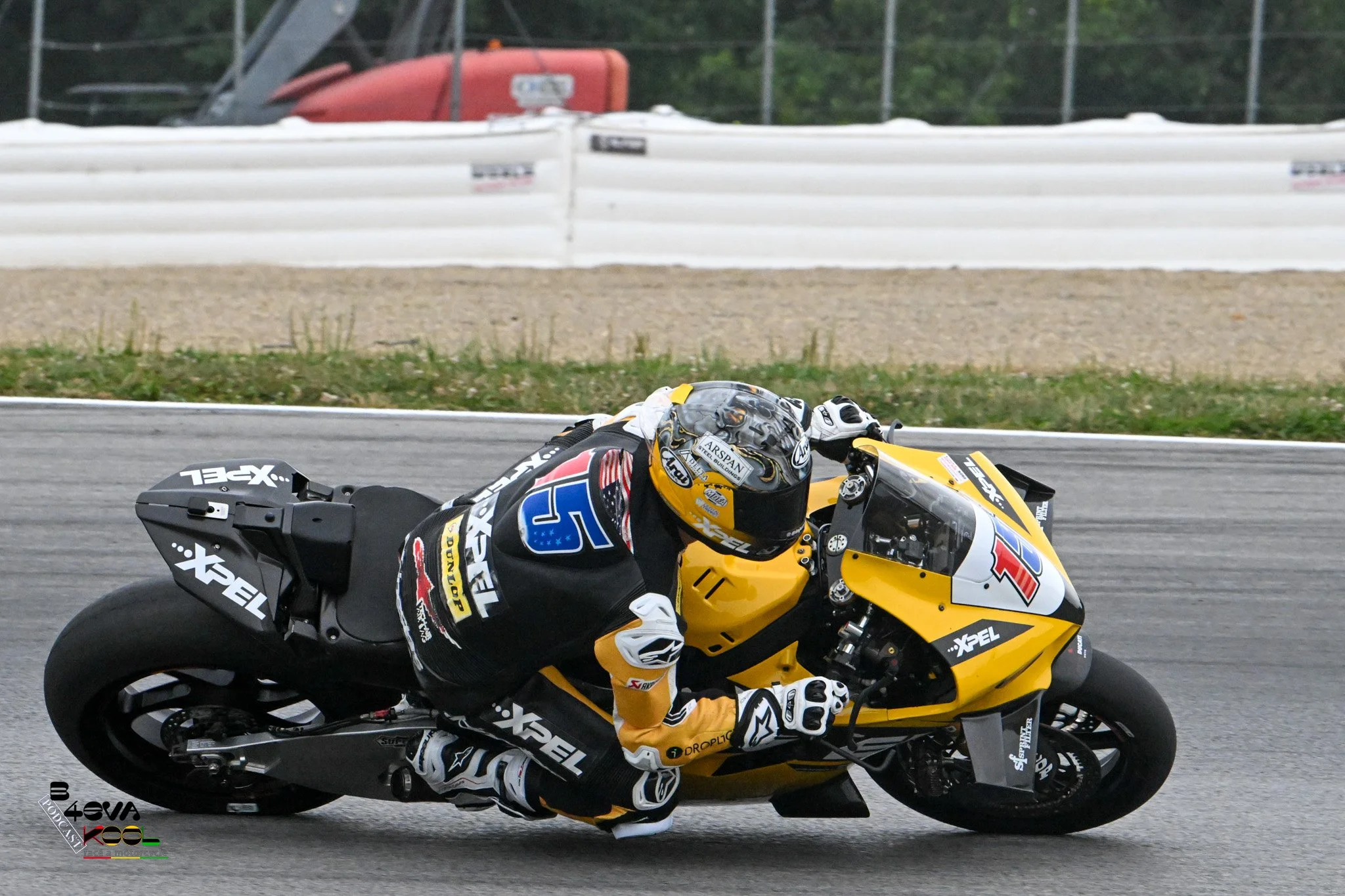 Motorcycle racer in yellow and black gear riding a yellow motorcycle on a racetrack.