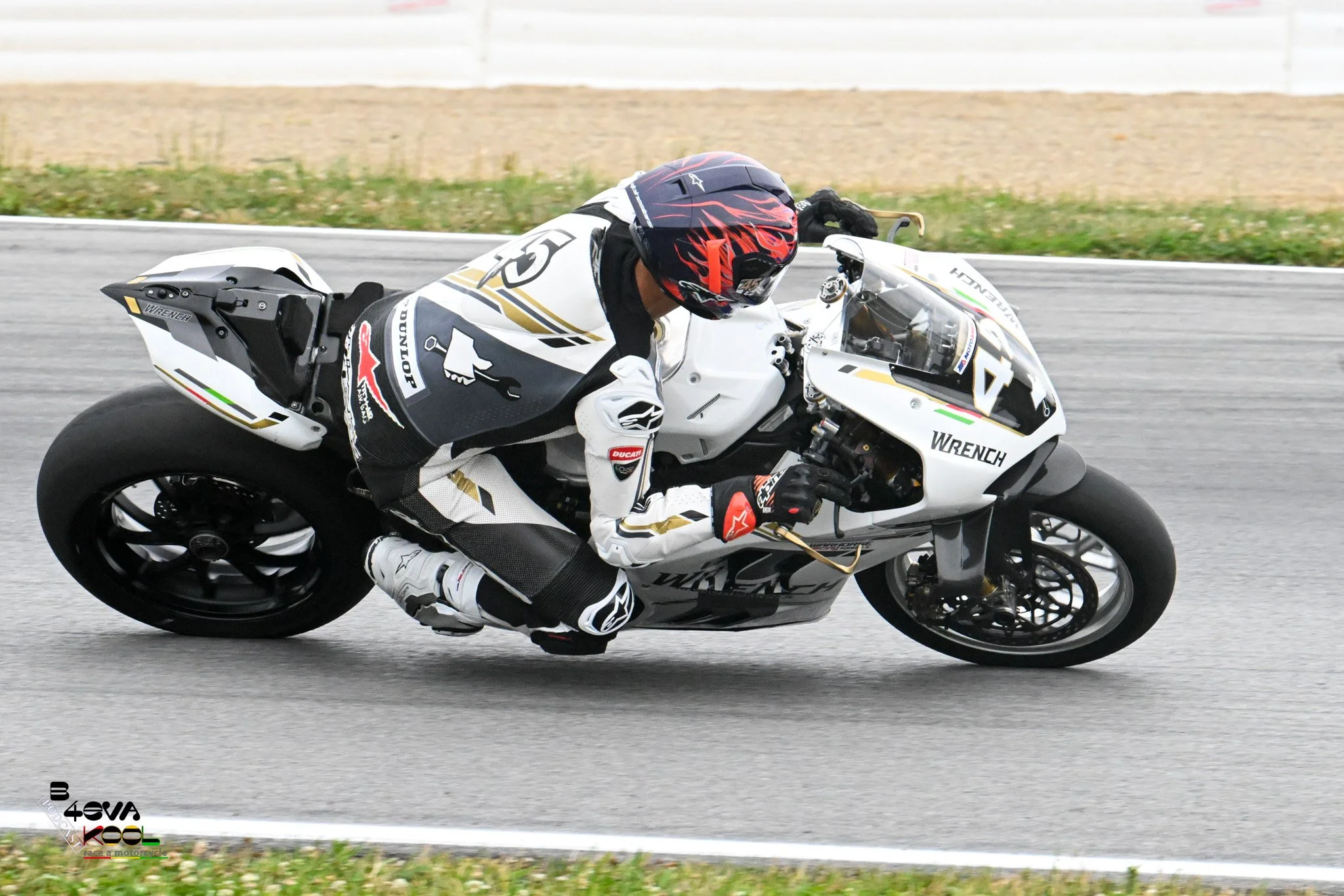 A motorcycle racer in full gear leaning into a turn on a racetrack.