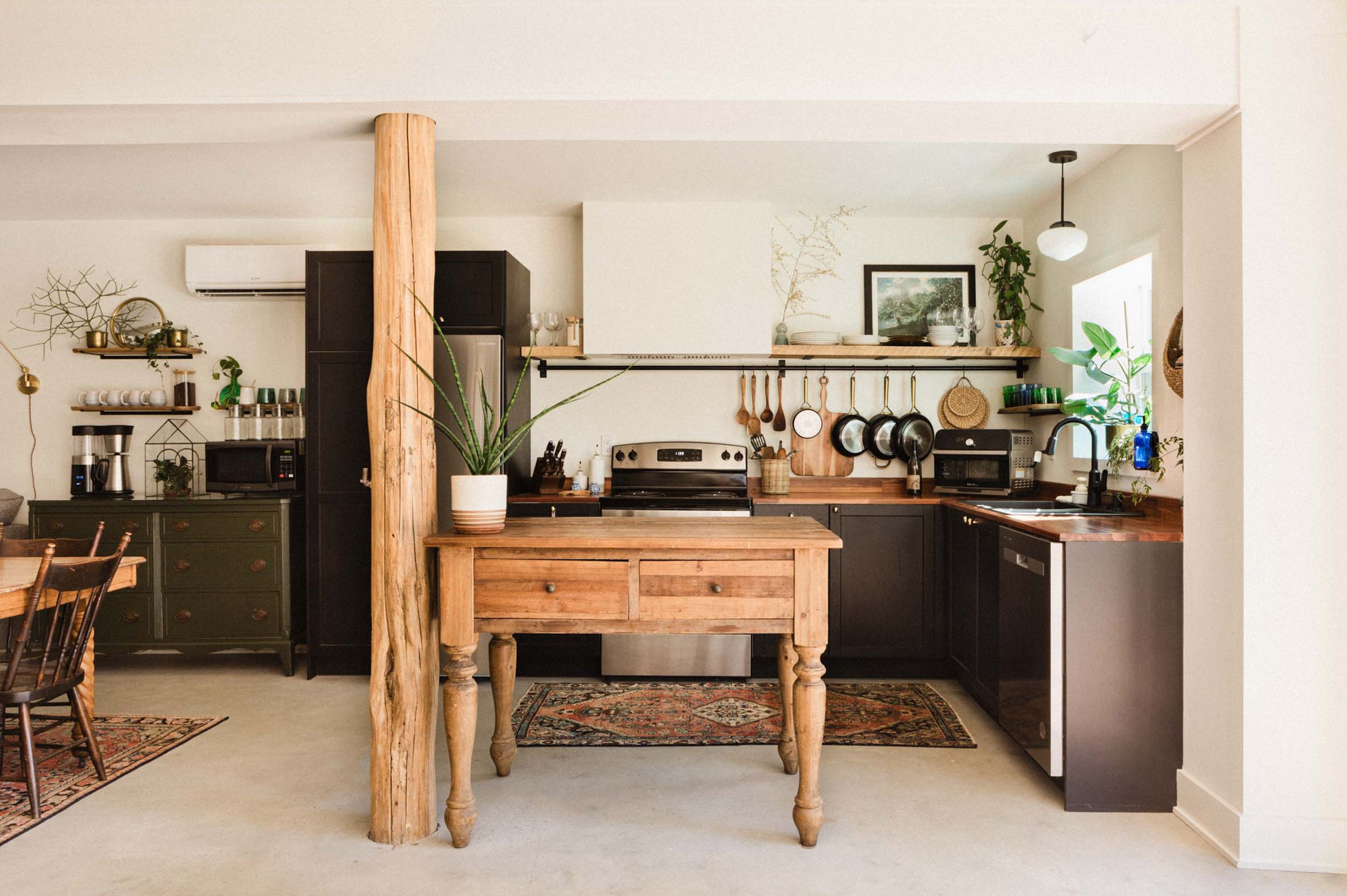Rustic kitchen photography: black cabinets, vintage wood island, and concrete floors.