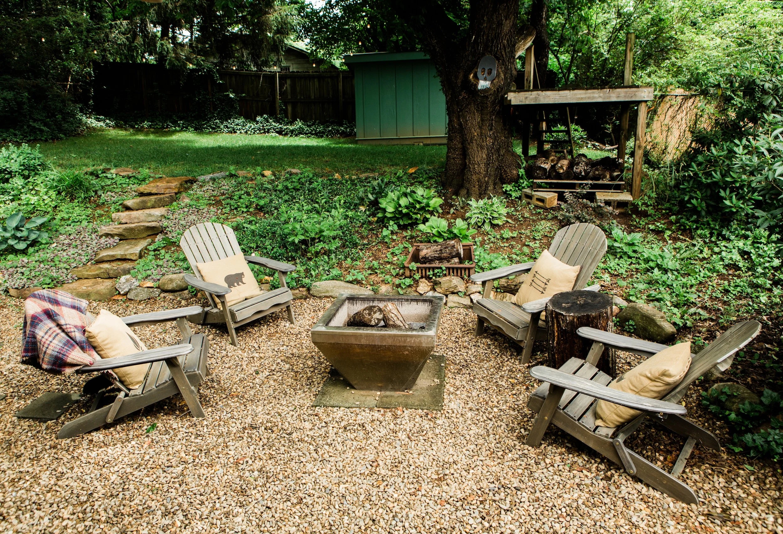 Outdoor living area featuring brown pebble gravel, Adirondack chair and fire pit.