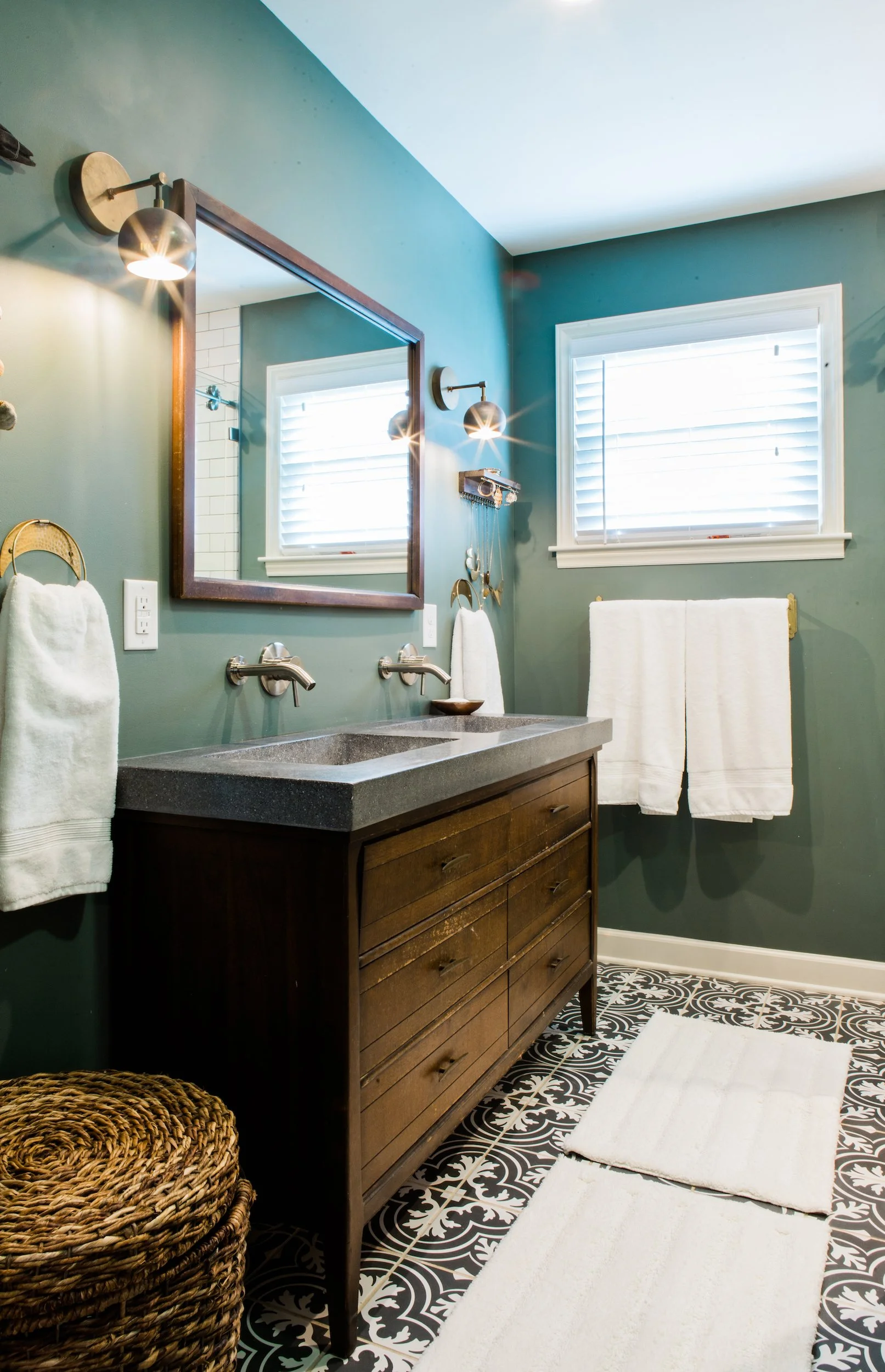 Modern bathroom with vintage wood vanity, concrete sink, green walls, and patterned floor tile.