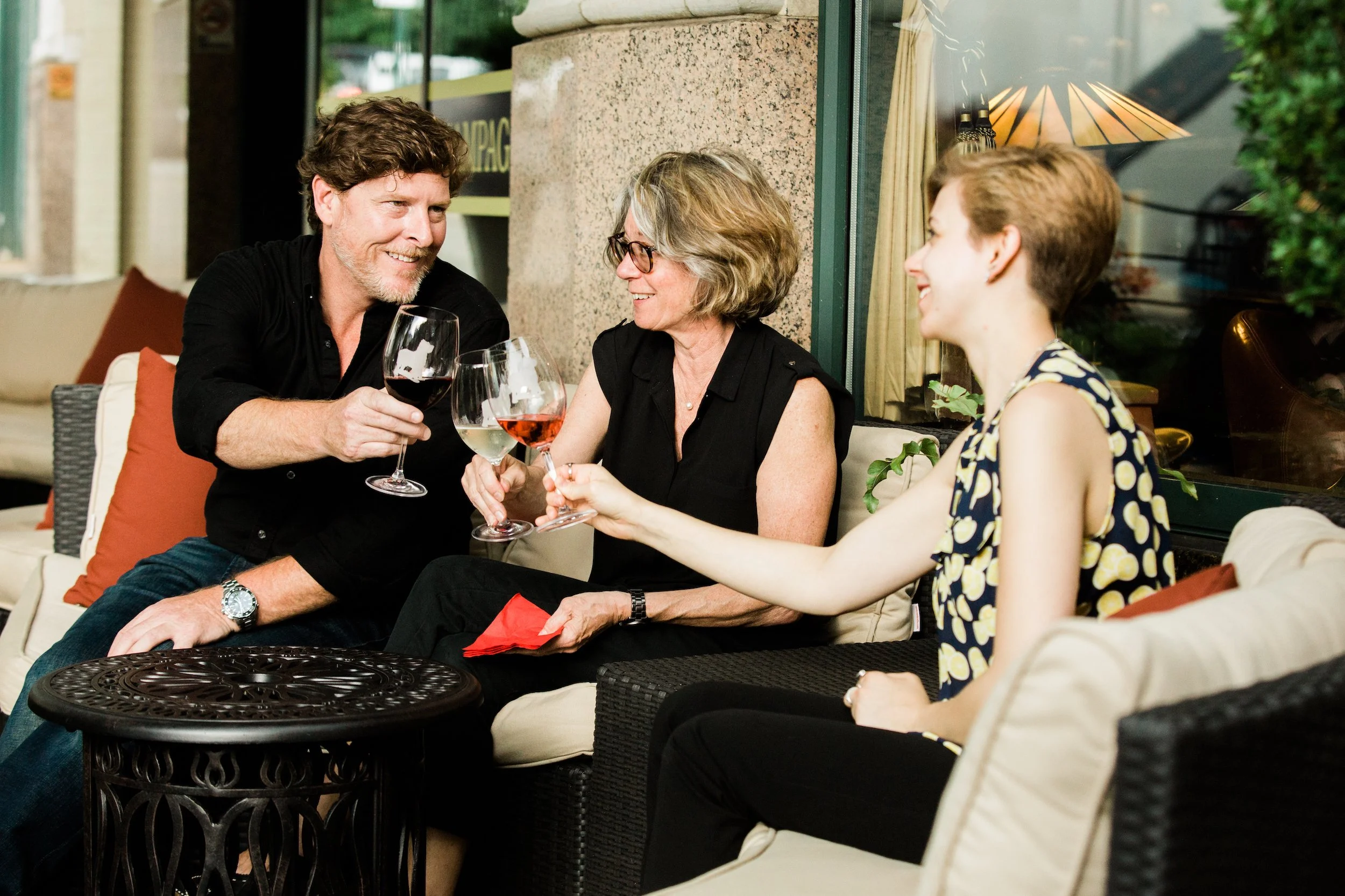 Three friends at an outdoor Asheville bistro drinking wine and toasting.