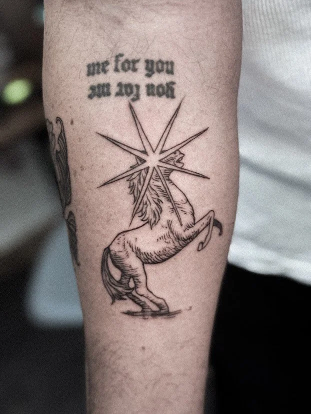 Tatuaje de un unicornio con una estrella y texto en inglés que dice 'me for you' y 'you for me'.