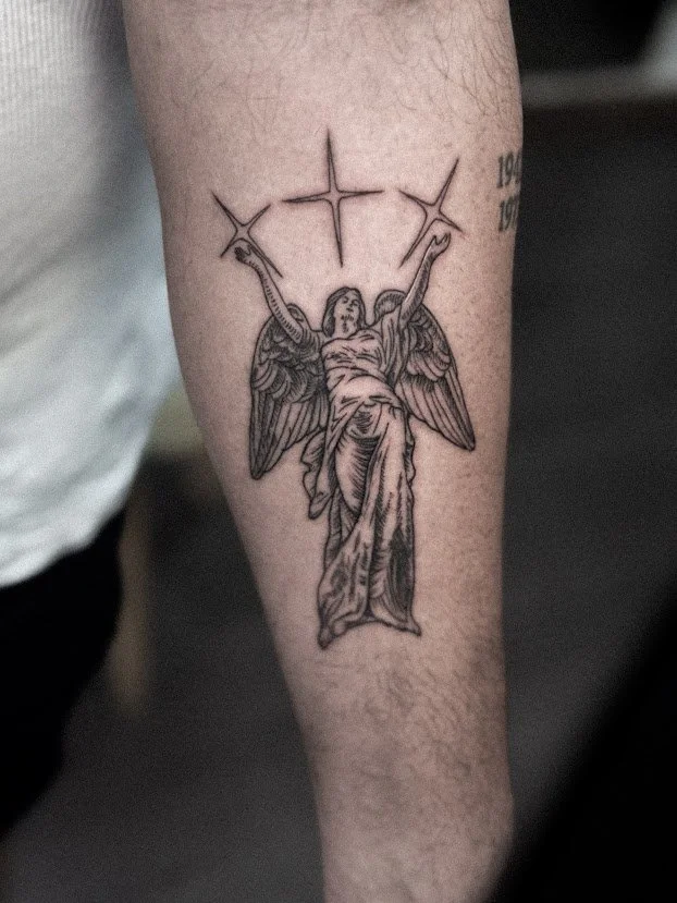 Tatuaje de un ángel con alas y vestido largo, levantando los brazos con una cruz encima.