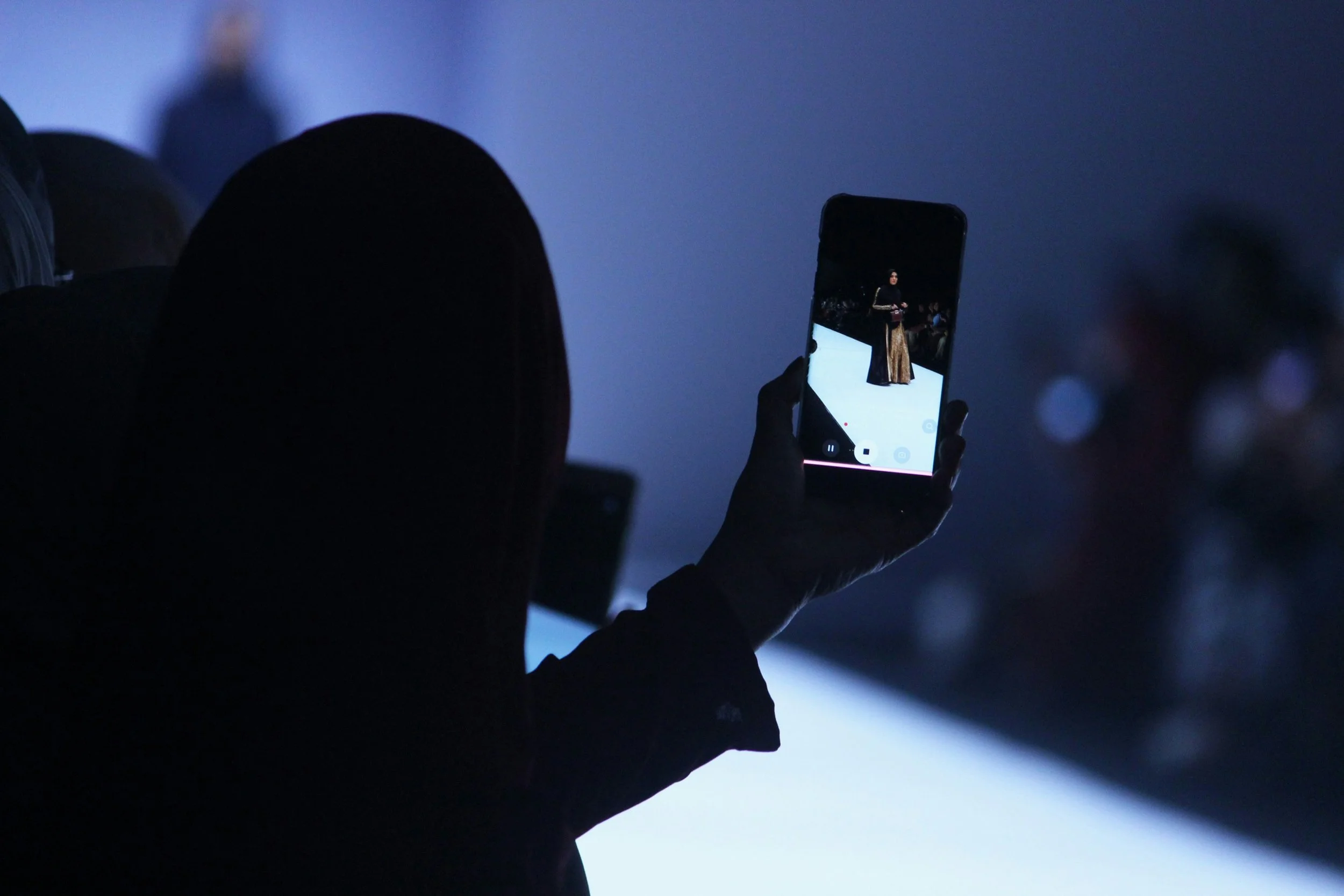An attendee records a runway show on a smartphone during Seoul Fashion Week 2026 at Dongdaemun Design Plaza, capturing the atmosphere and digital energy of Korea’s leading fashion event.