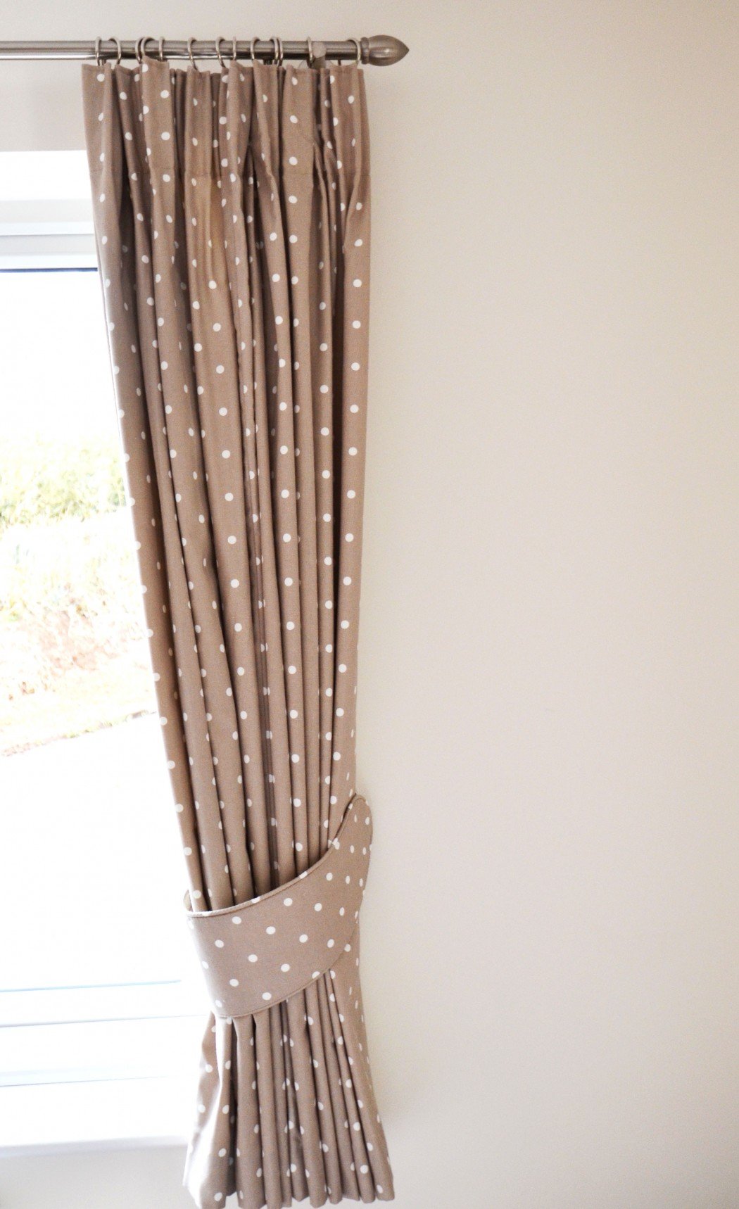 Polka dot curtains tied back next to a window