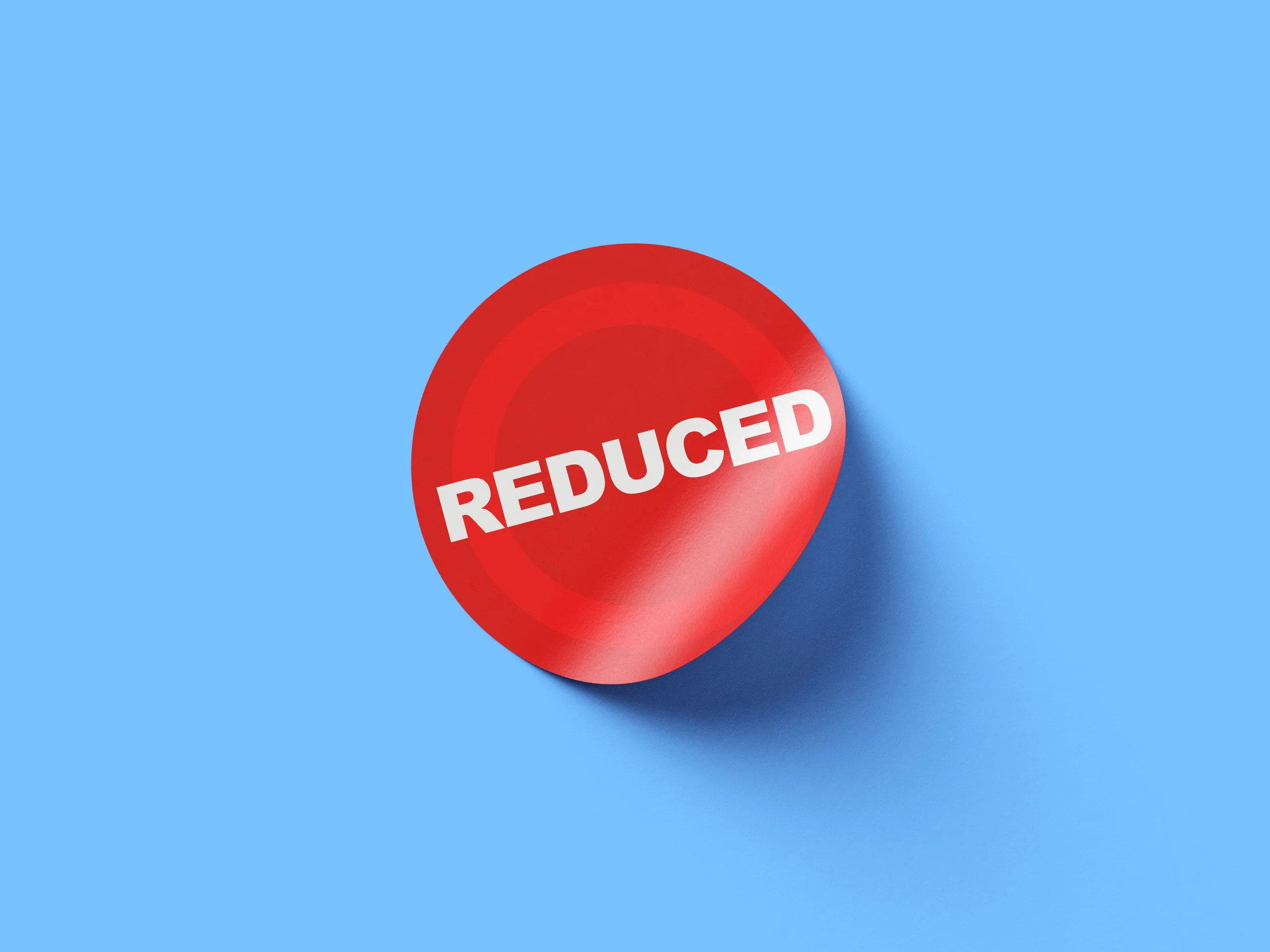 A red circular sticker on a blue background. the sticker says "reduced" and has a simple tonal style.