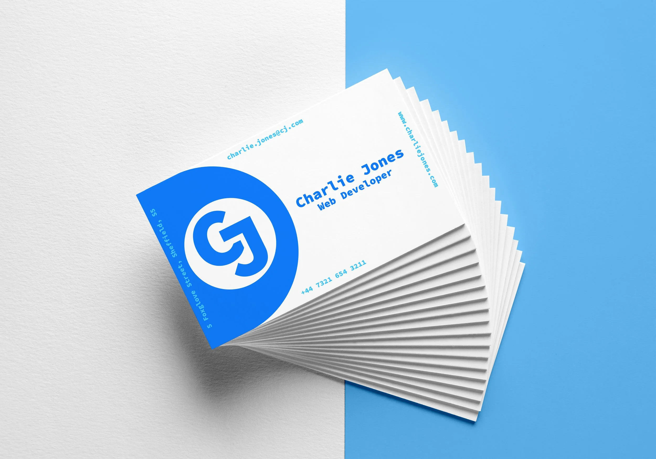 White business cards with vibrant blue accents, on a split blue and white background. There are multiple business cards fanned out on-top of one another.