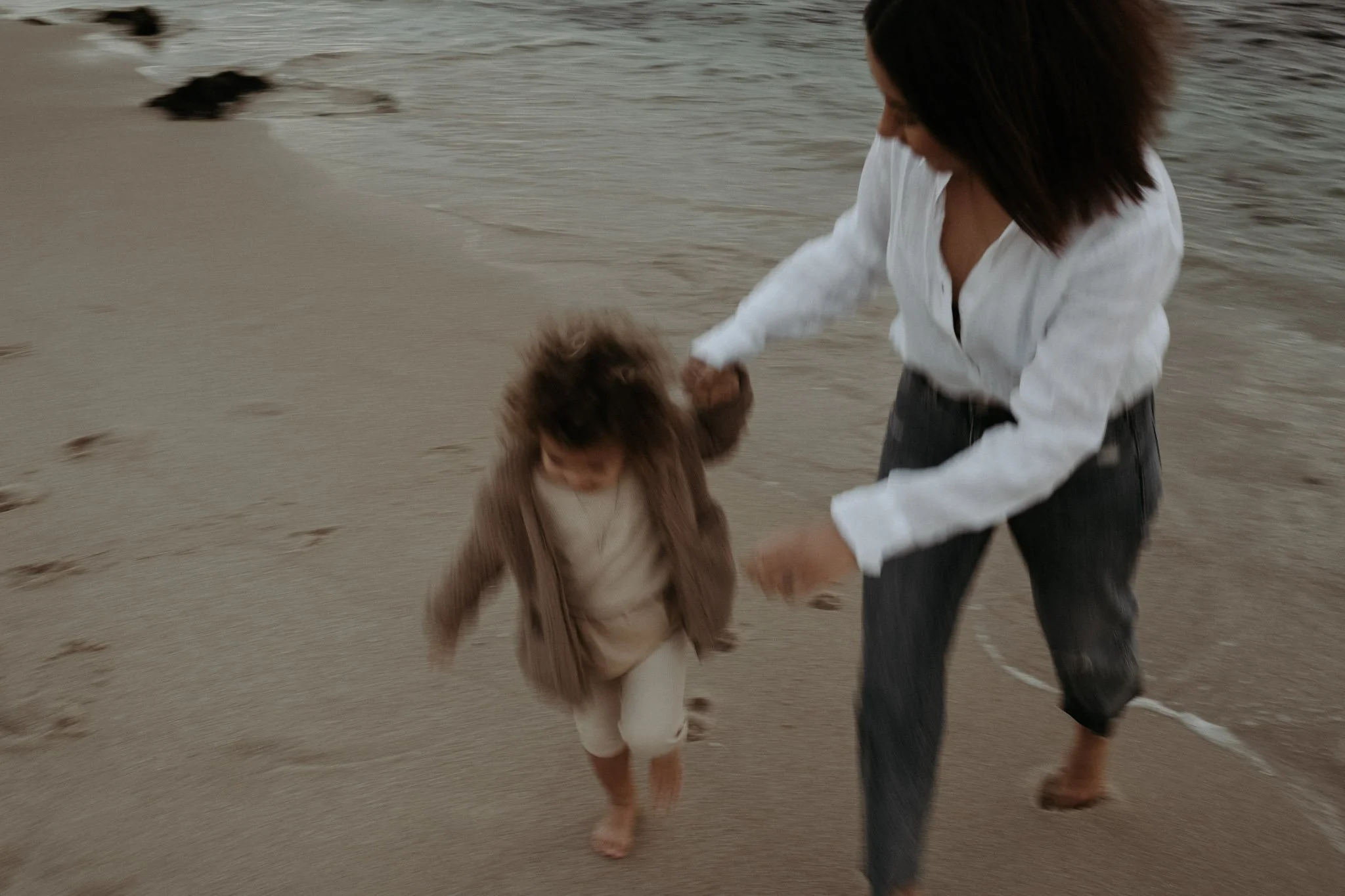 Blurred image of a woman and child running on a beach
