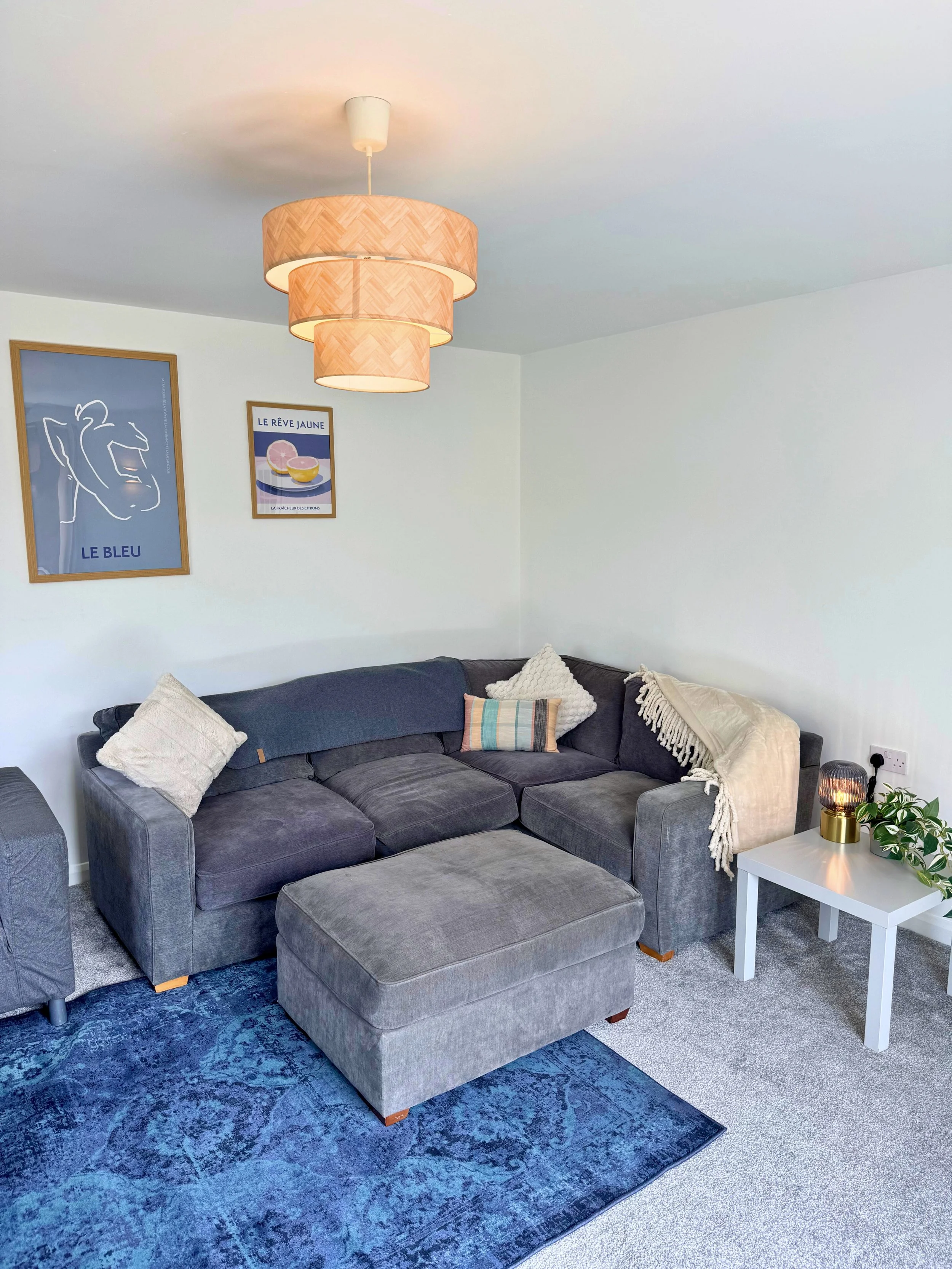 Hotel room with neatly made bed and white pillows, dark wood headboard, and wall-mounted lamp.