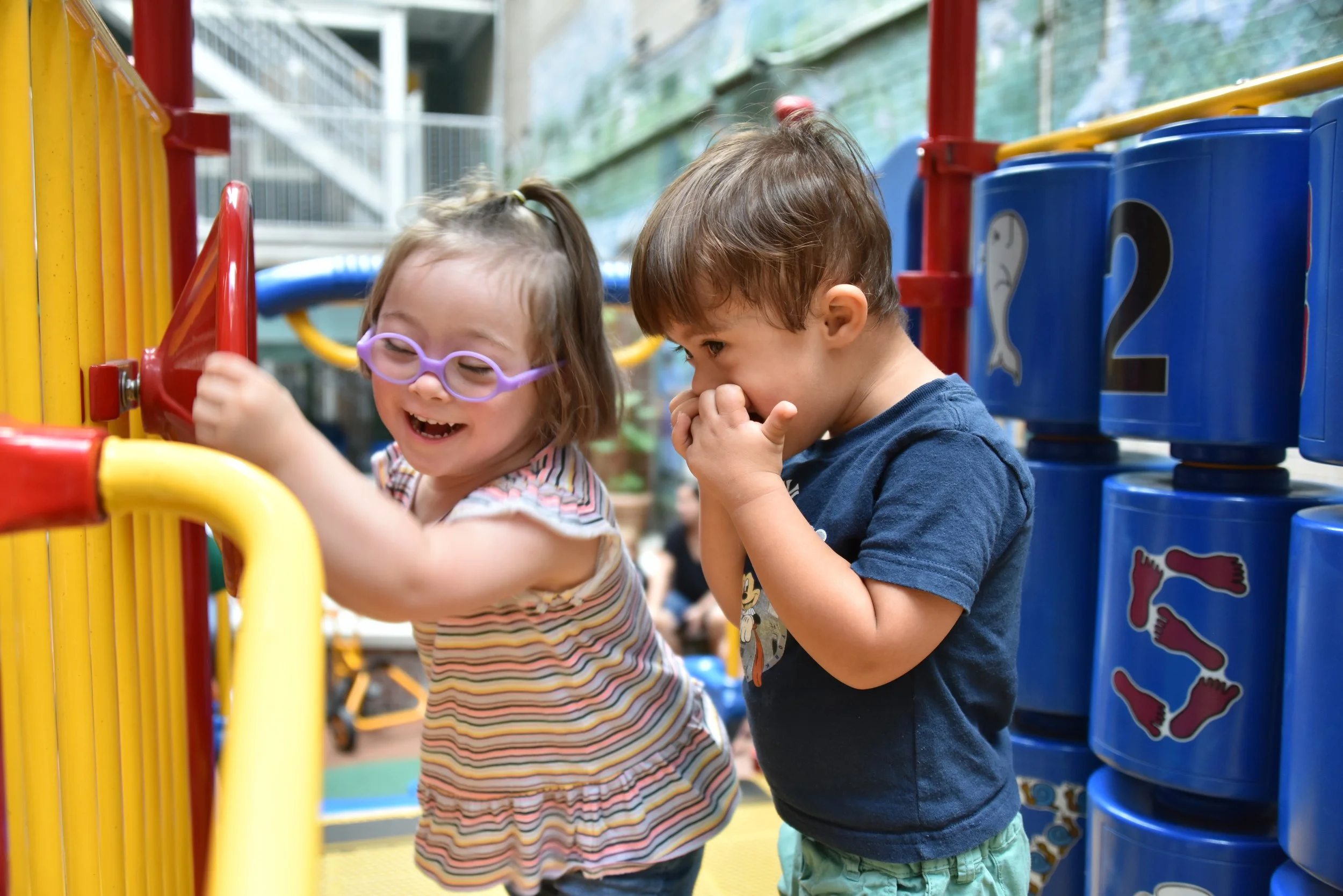 Two children laughing by a play structure.
