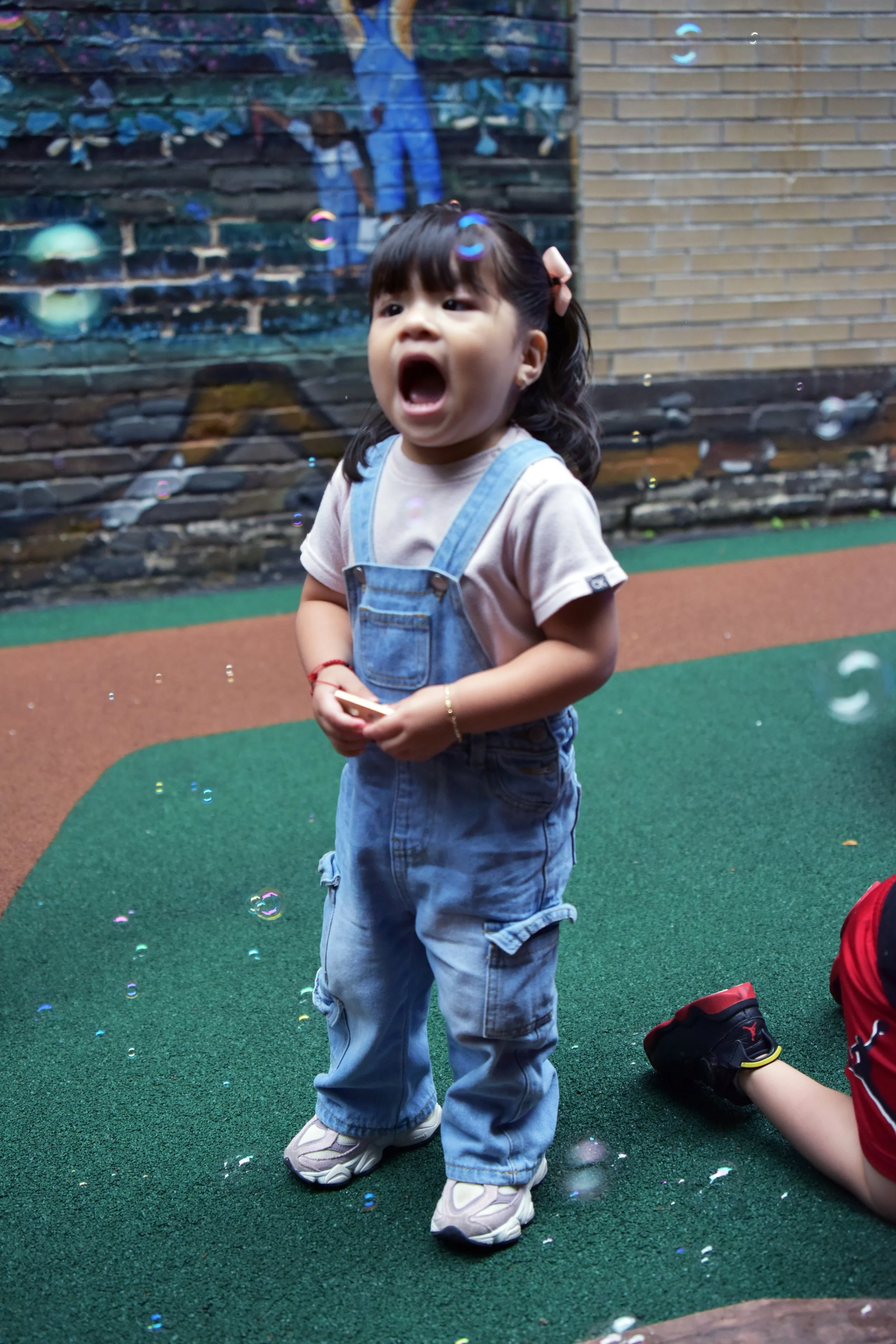 Girl standing with her mouth open as bubbles fall around her.
