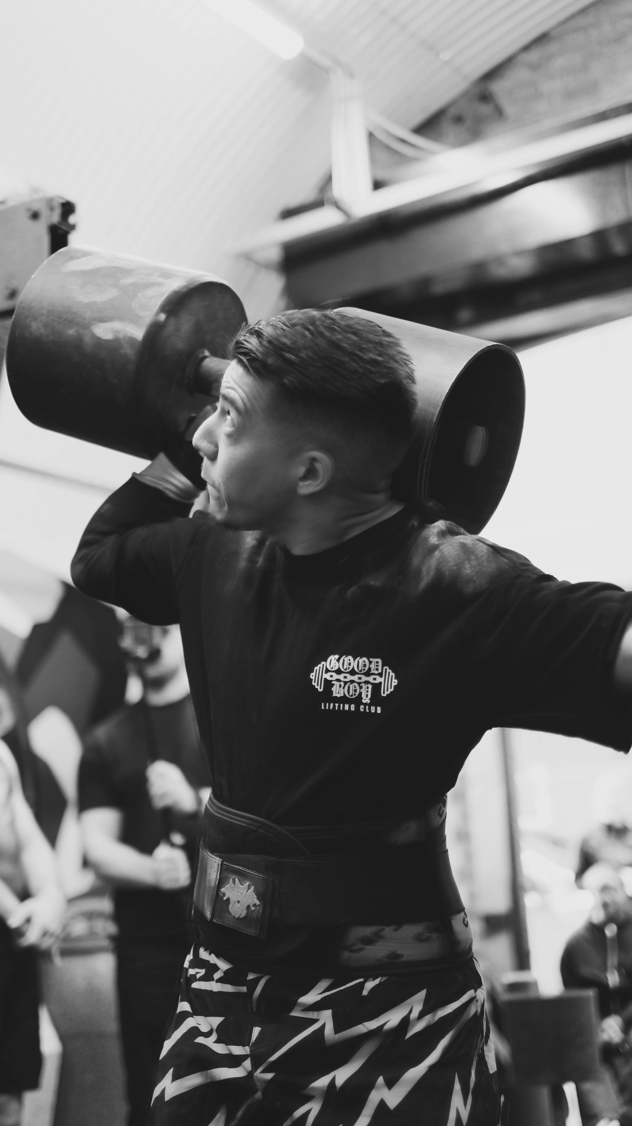 trans man pressing a circus dumbbell at Queerstrong