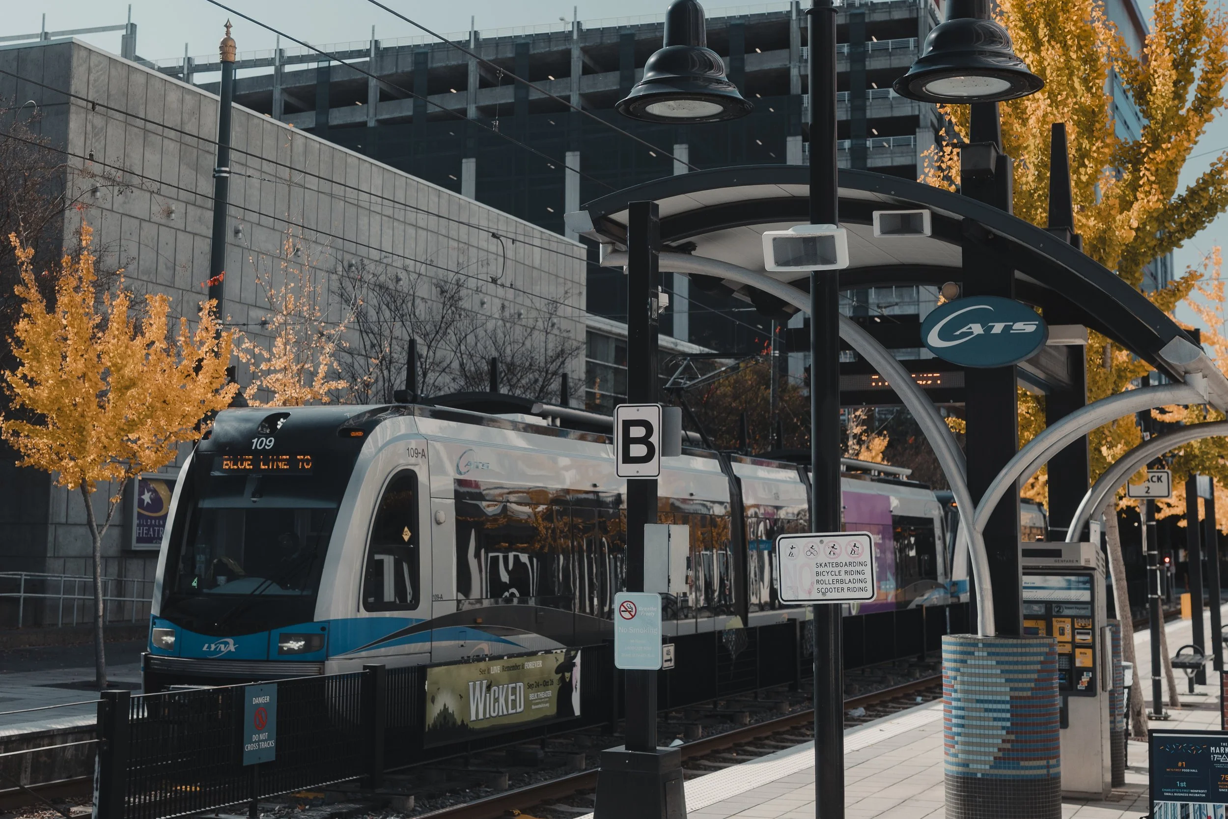 Sleek light rail train passing through an urban station platform in autumn, representing modern city life, travel, and a commuter lifestyle.