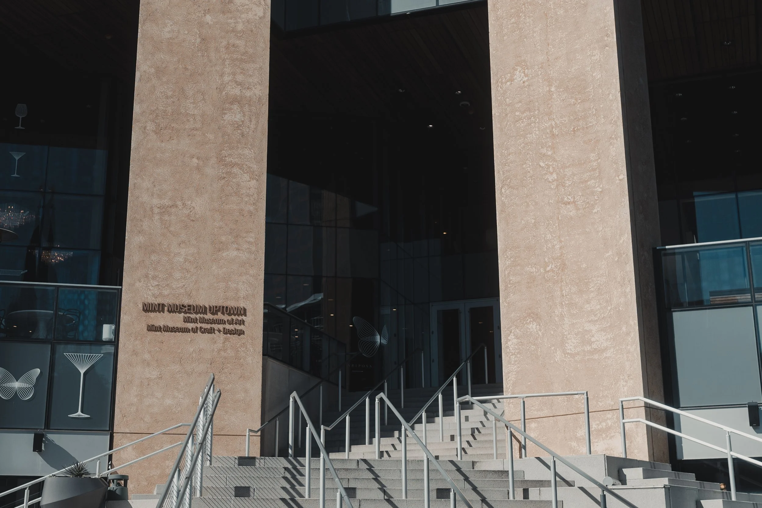 Grand, modern building entrance with stone pillars and glass, providing a sophisticated backdrop for lifestyle and apparel photography.