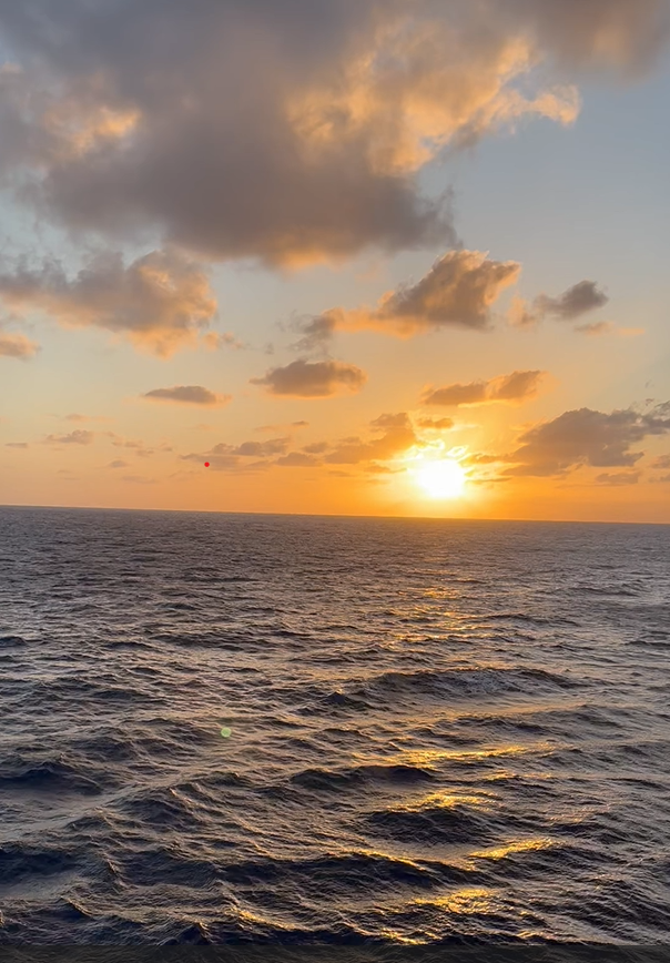 Sunset over the ocean with clouds in the sky.