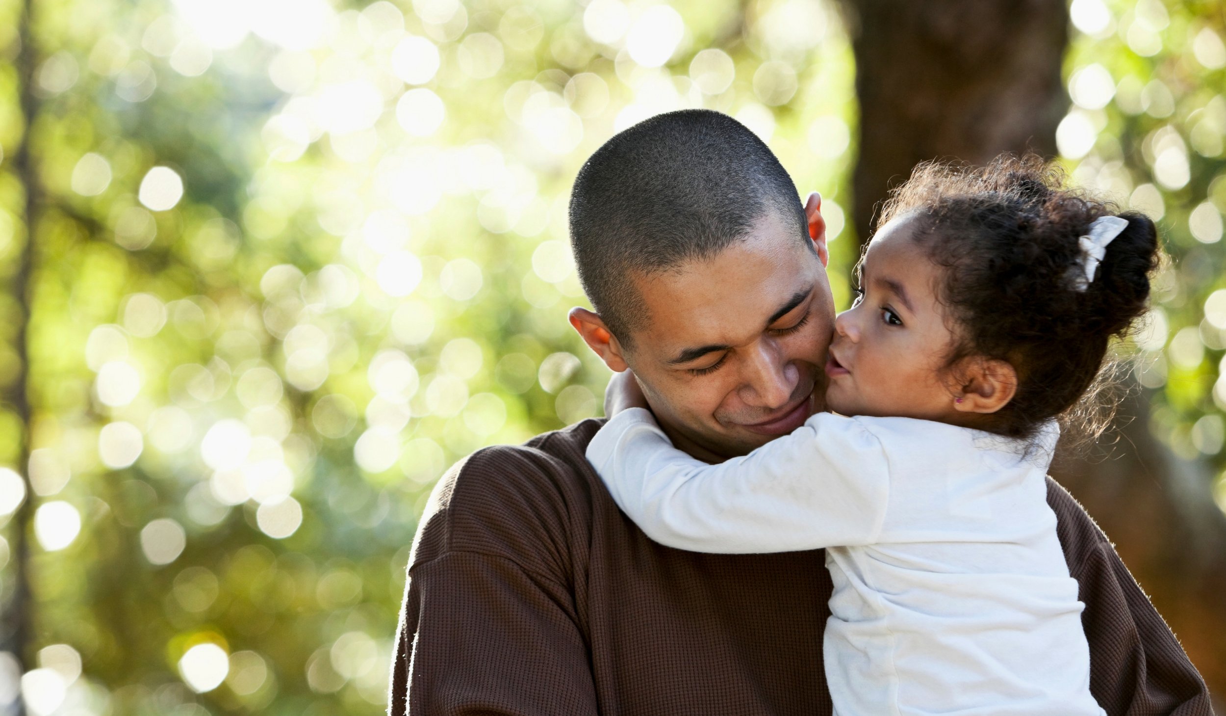 A father hugging his daughter while being outside in nature  