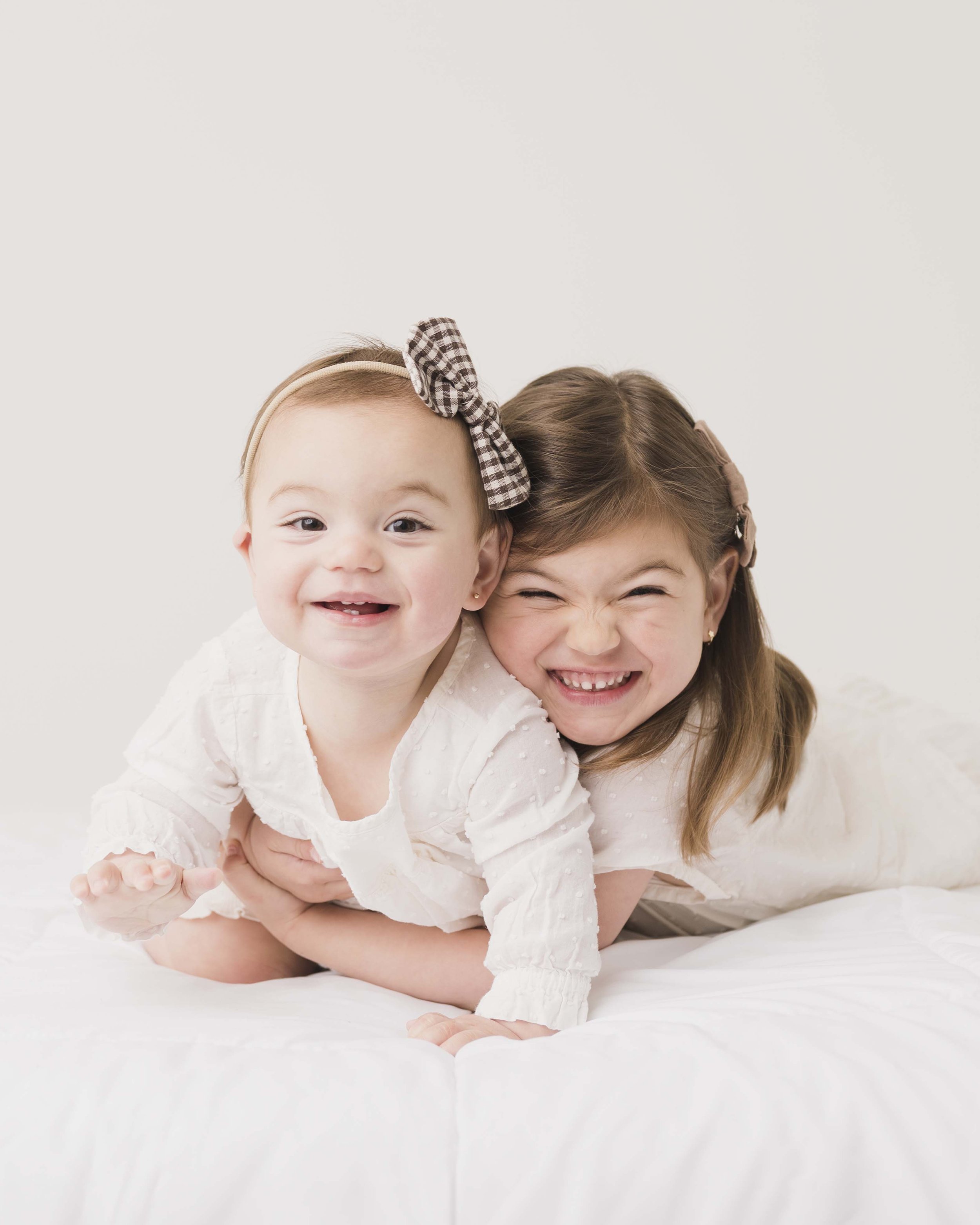 soft studio portrait of two smiling sisters in neutral outfits Charlotte NC