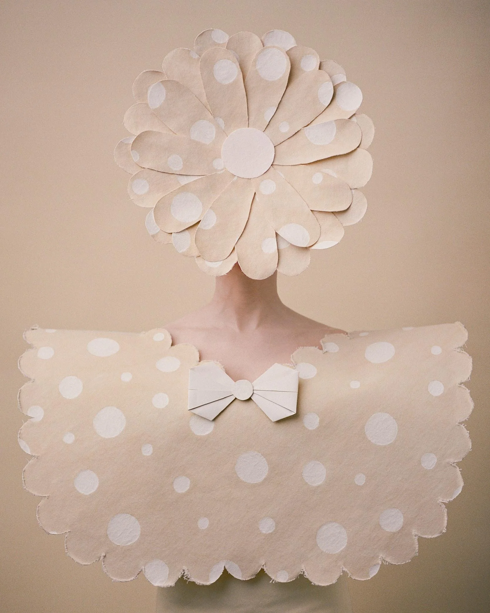Fine art portrait of a figure wearing a soft beige sculptural costume with a floral headpiece