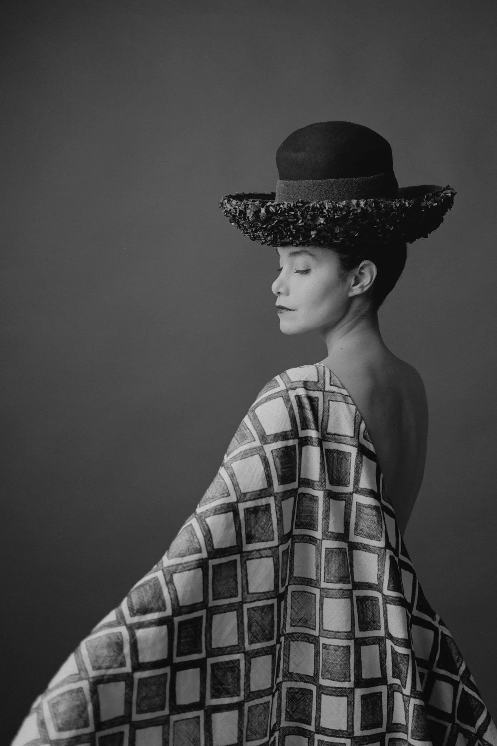 A black and white portrait exploring form, movement, and texture through soft light and a sculptural pose.