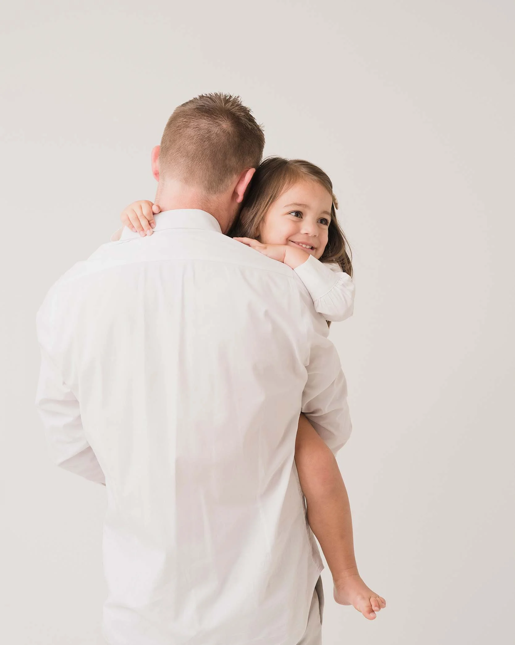 Father holding his young daughter during a soft, minimal studio portrait — classic children and family photography in Charlotte, NC