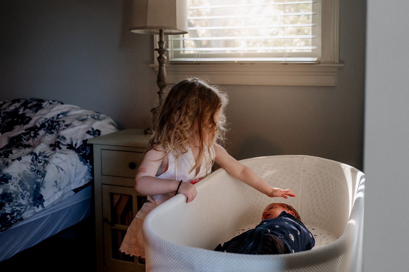 Little girl looking in the bassinet at her newborn baby brother at home in Atlanta