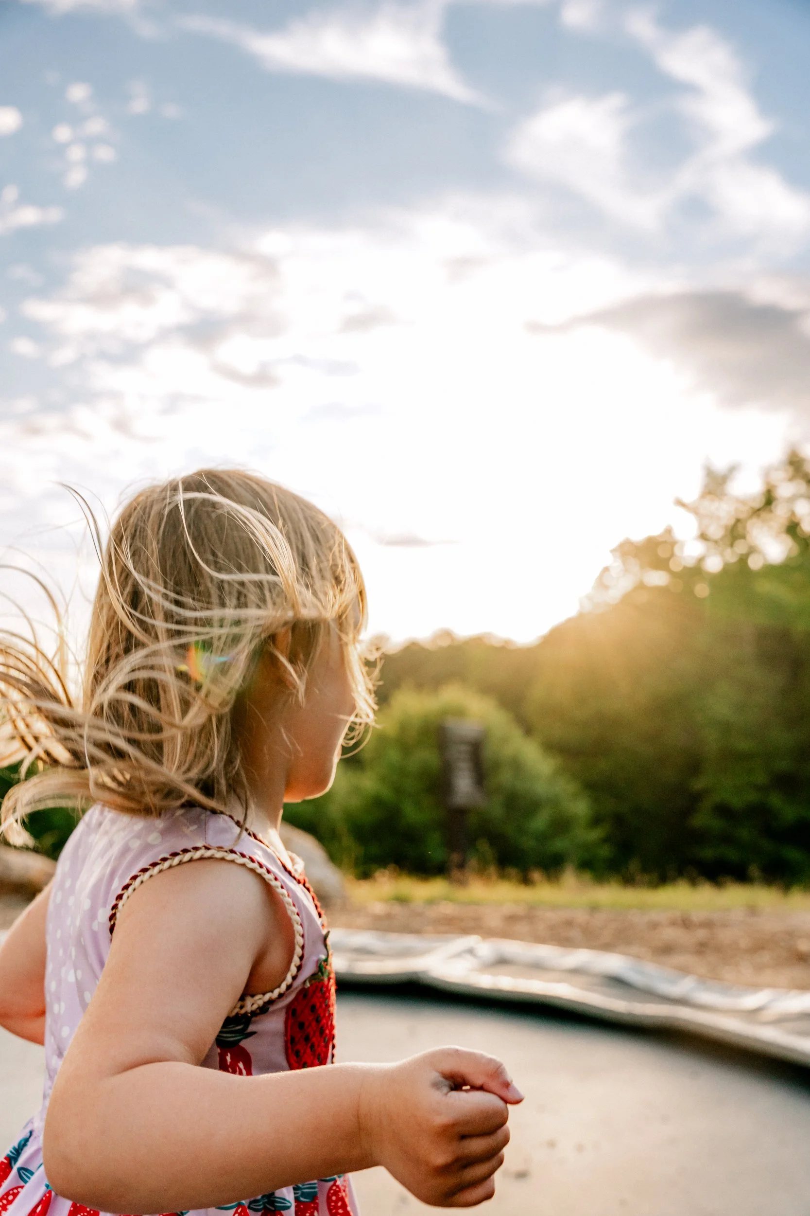 girl on trampoline with sunset behind her