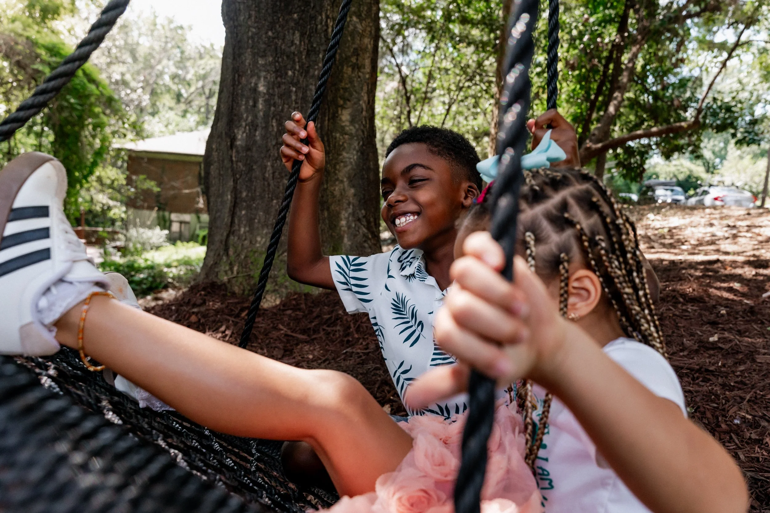 Siblings swinging and laughing in their front yard