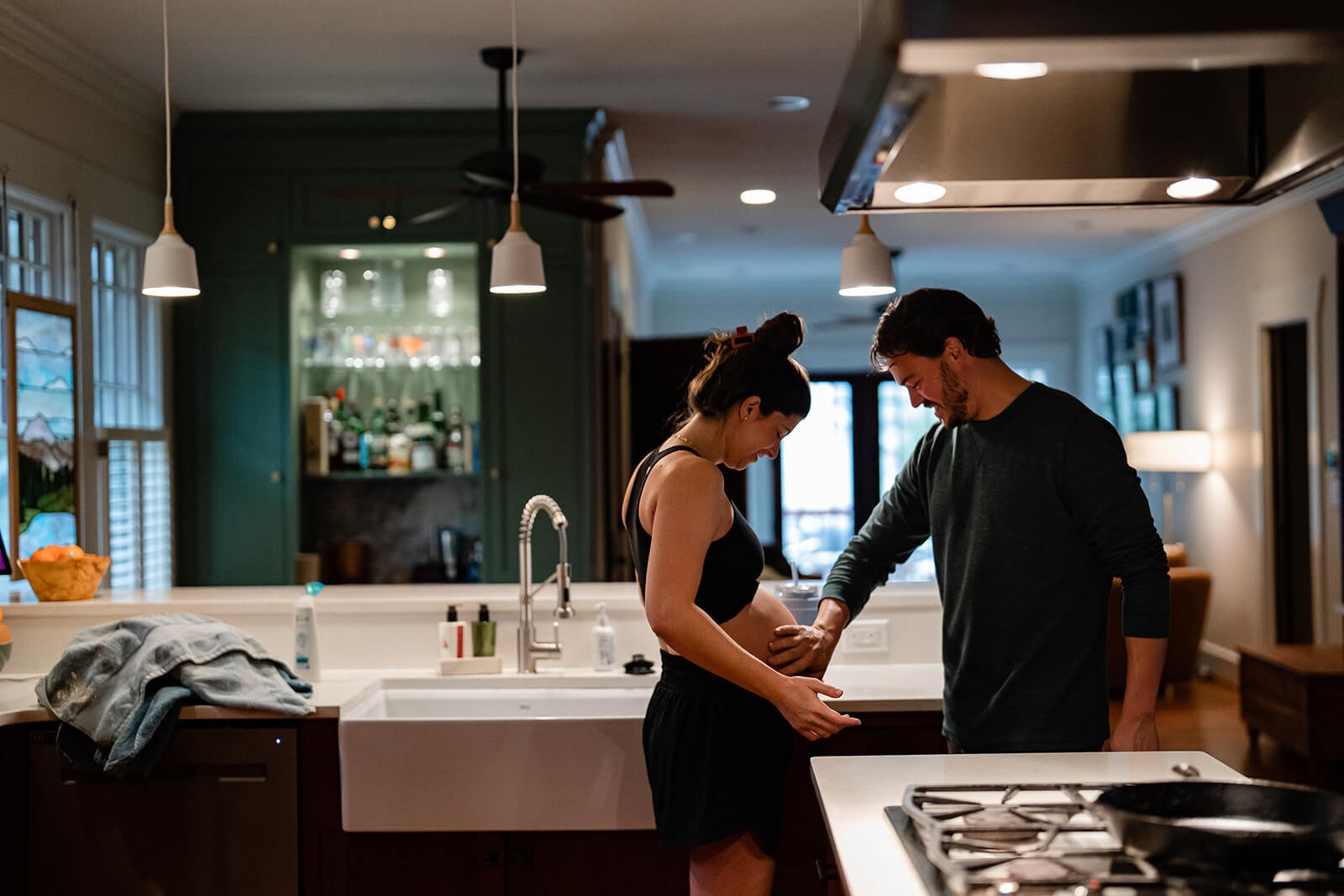 Dad feeling his pregnant wife's belly in their Decatur kitchen at home