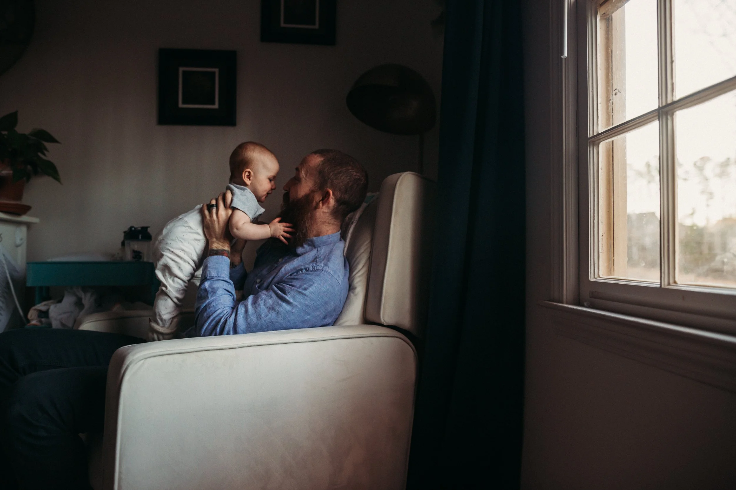 Dad holding up his 6 month old baby in the nursery