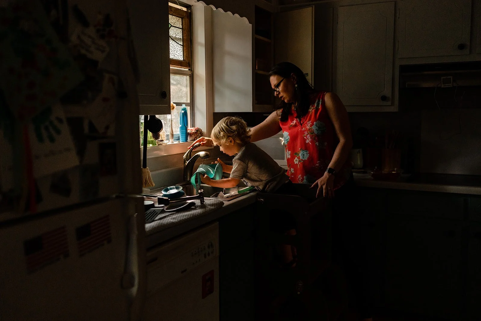 Mother and son washing dishes at home in their kitchen
