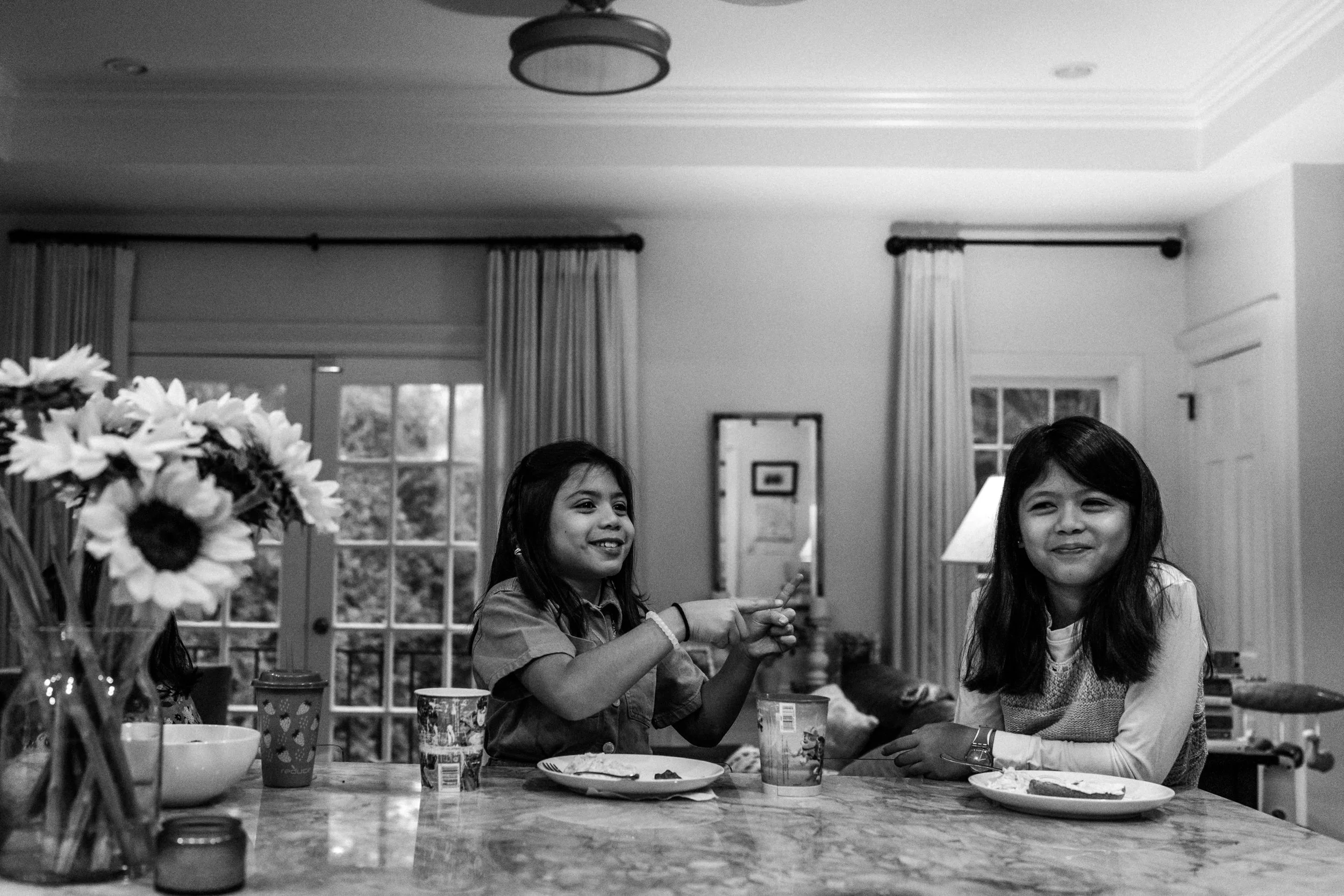 Tween sisters laughing in the kitchen over breakfast