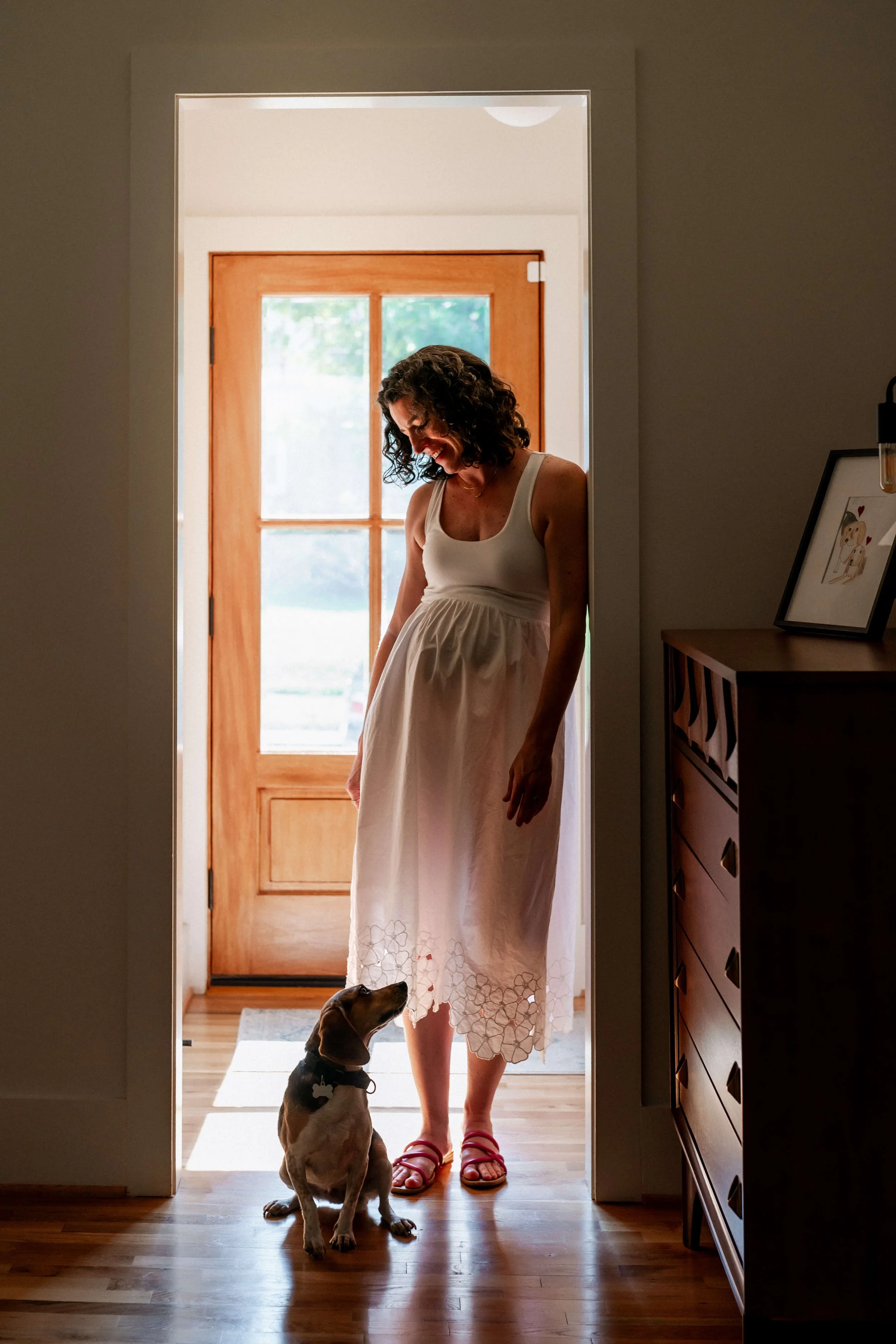 Pregnant mom smiling at her dog in the doorway of her Atlanta home