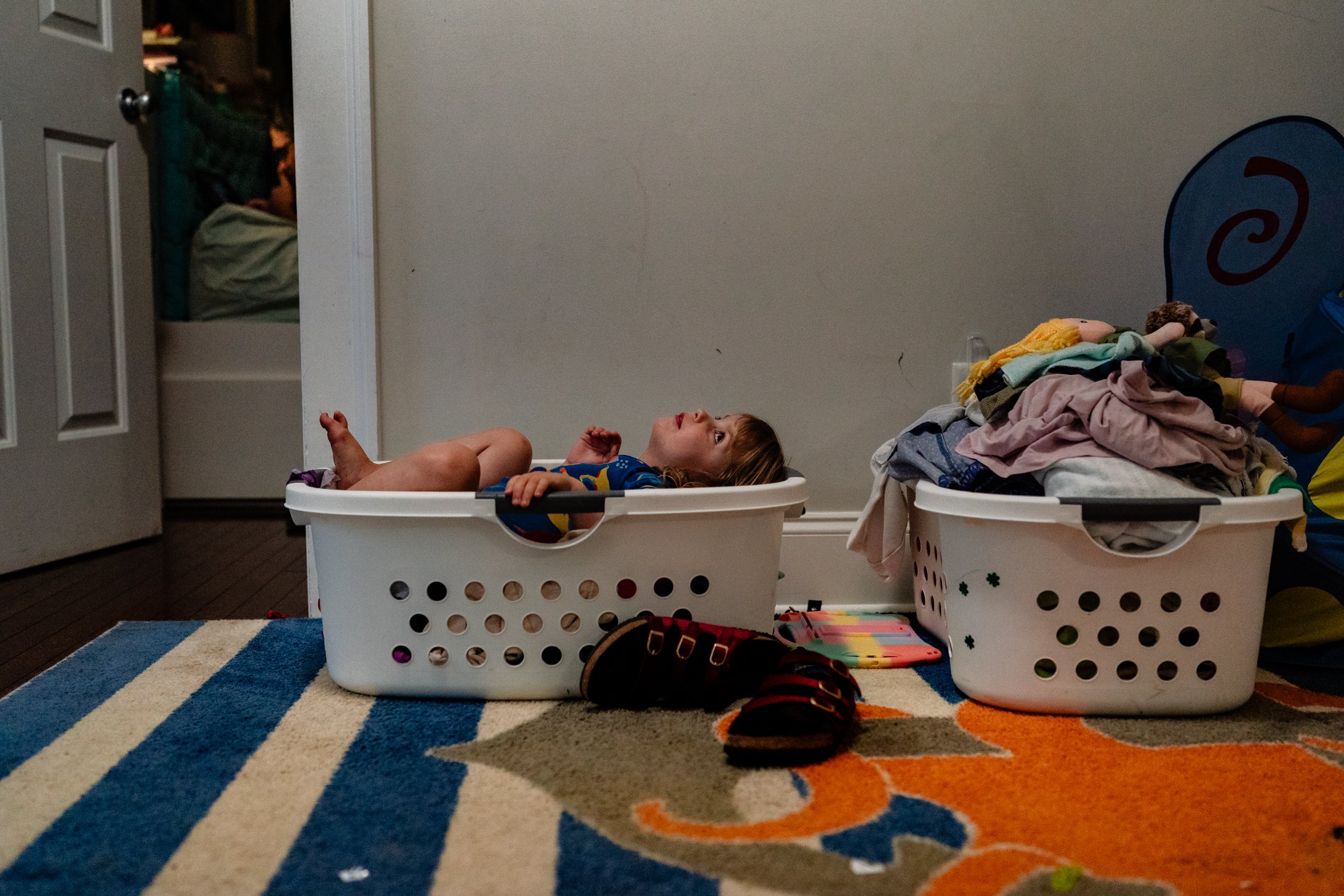 little girl hiding in a laundry basket at home