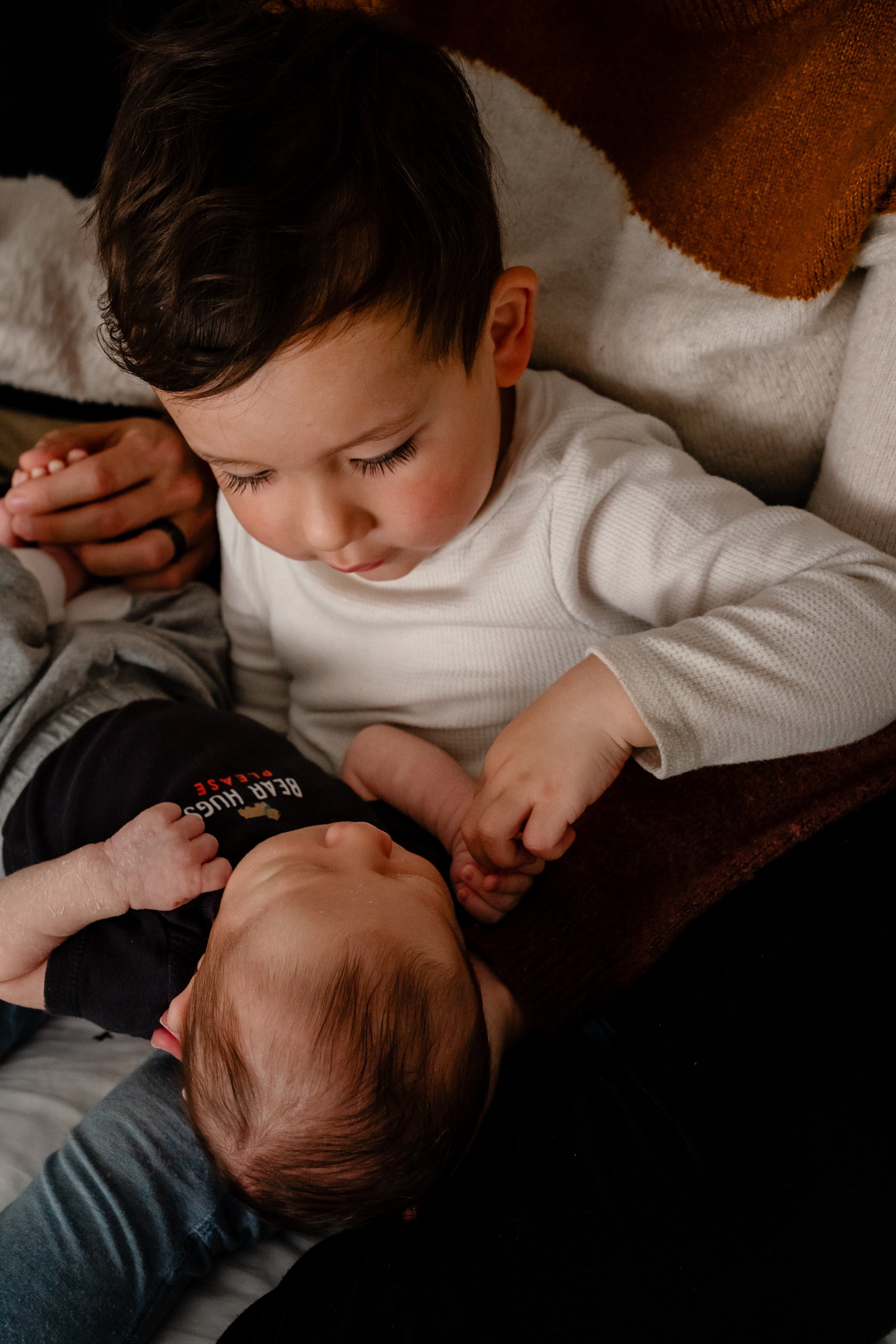 Toddler looking at his newborn baby brother