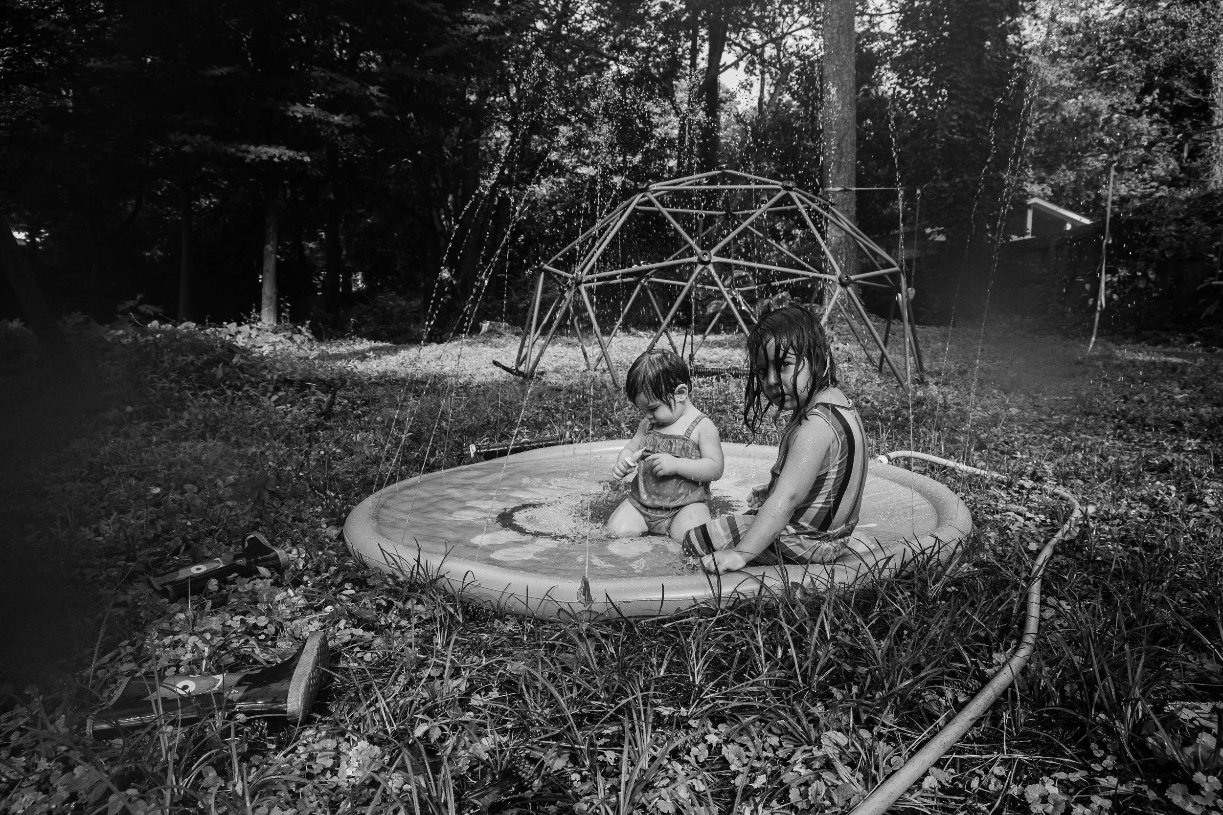 Sisters playing in the sprinklers in their backyard