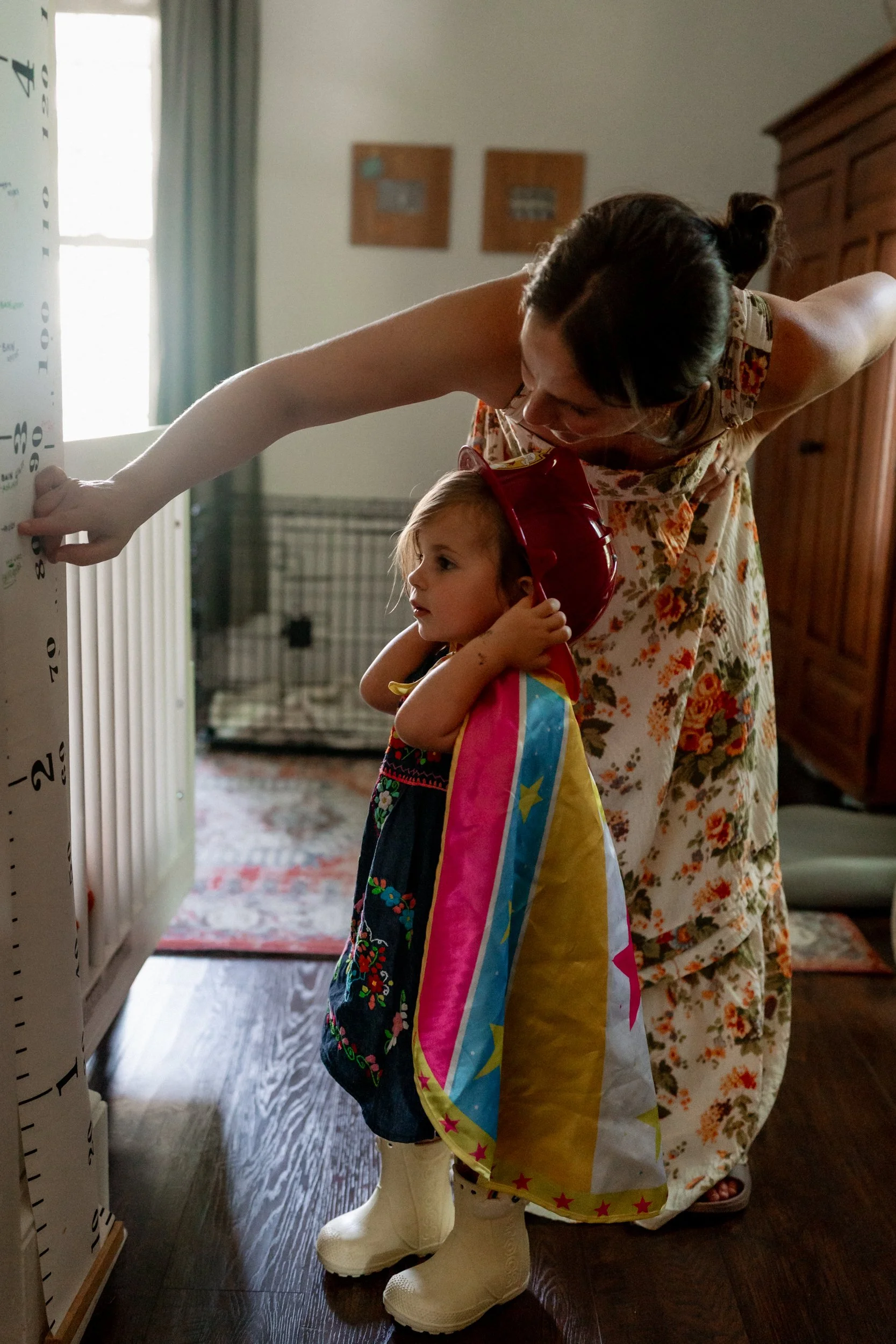 Mother showing her daughter where she is on a growth chart at home