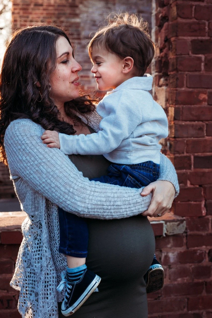 pregnant mom holding her toddler on her belly at a park in Atlanta