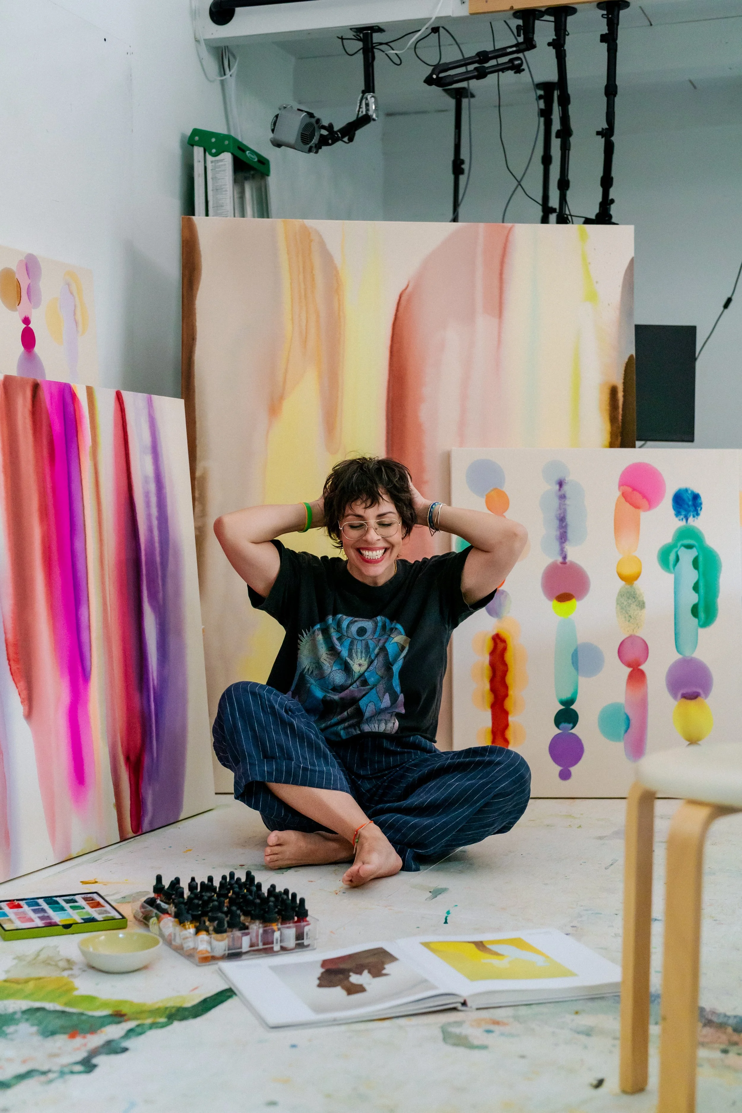 Woman sitting on the floor of her painters studio laughing