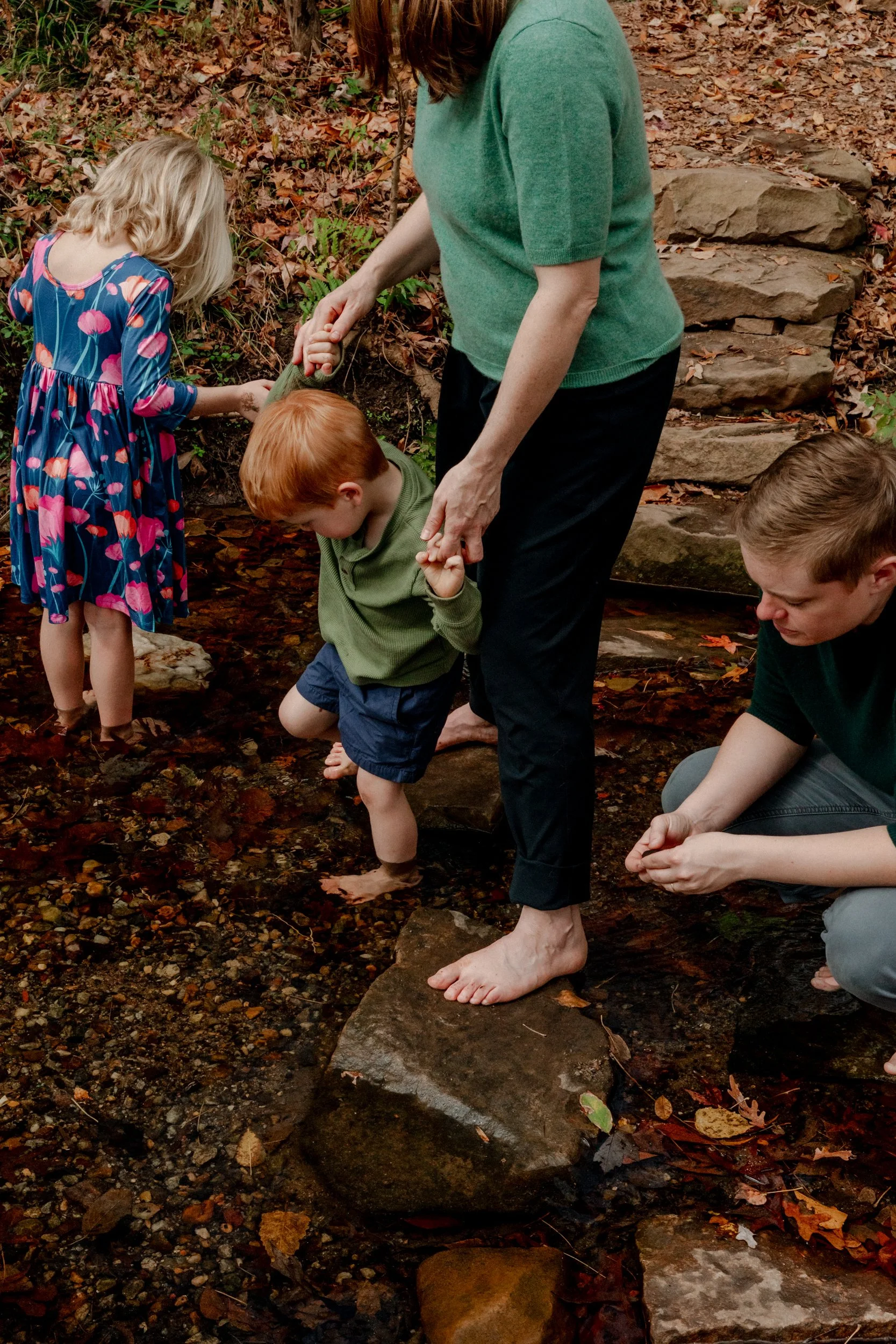 Family playing barefoot in a creek near their home