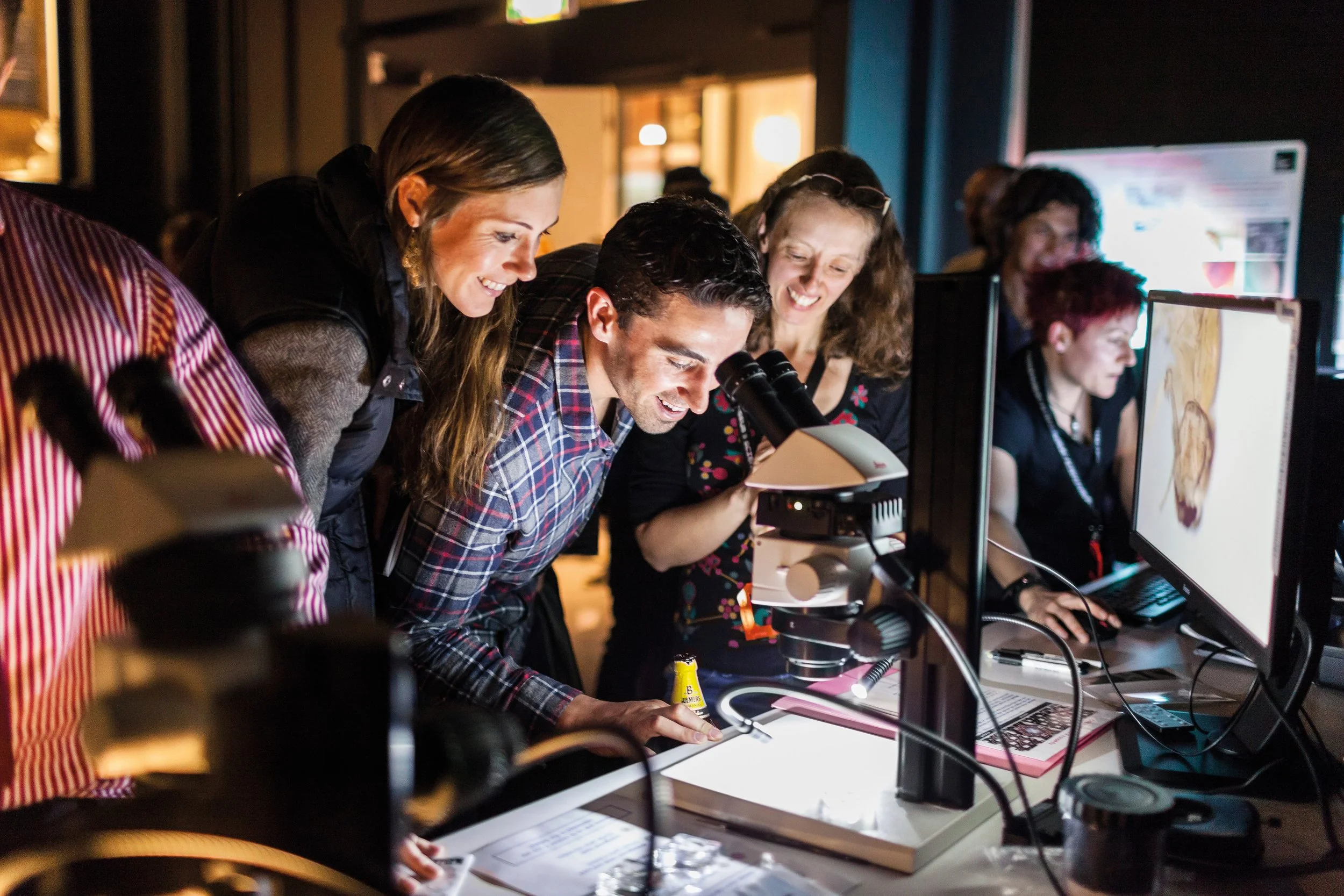 Group of scientists examining a sample under a microscope in a laboratory.