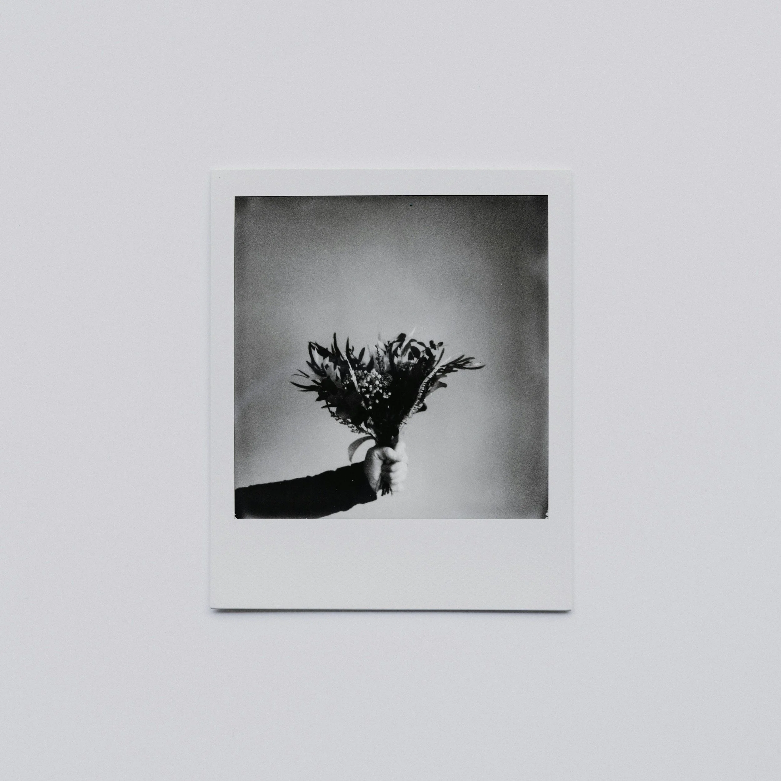 Black and white photo of a hand holding a bouquet of flowers.