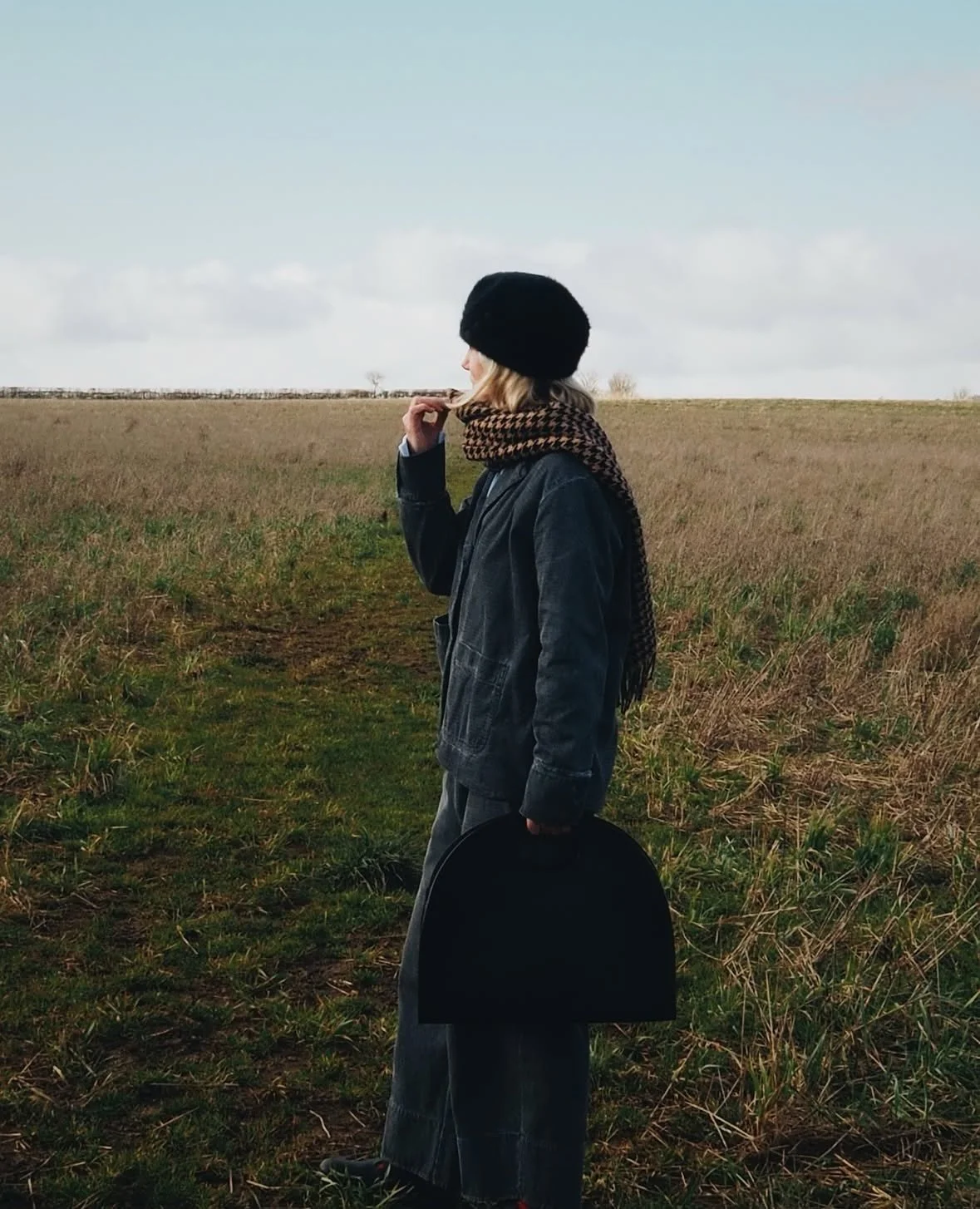 Lady in a field holding a black large statement tote bag with cut out handle