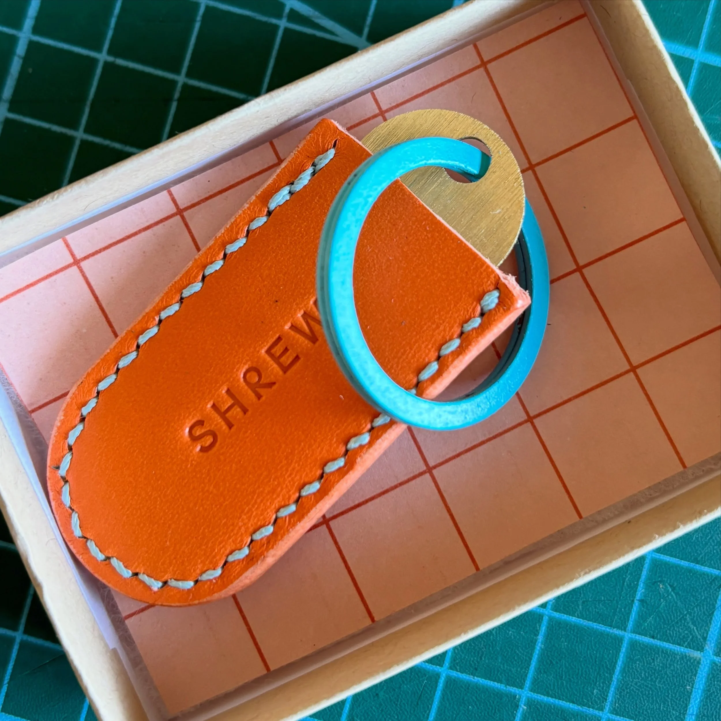 Looking for the perfect antidote to a bunch of boring keys?

A Leather and Brass Pop! Keyring in orange veg tan leather with aqua handstitching, split ring AND your initials on the reverse should do the trick! Especially when it comes in a cute littl
