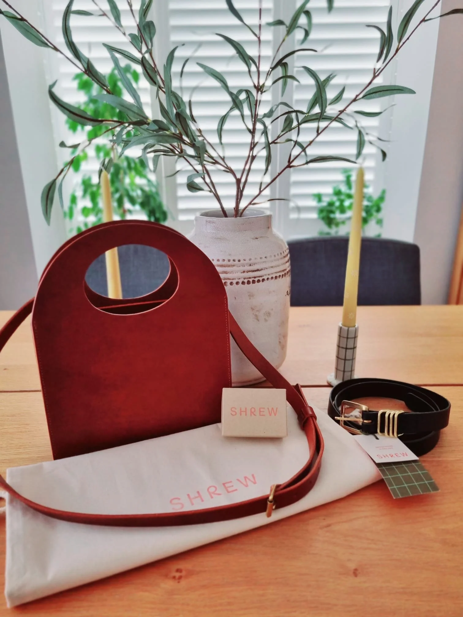 Small brown leather statement cross body and tote bag on a tabletop
