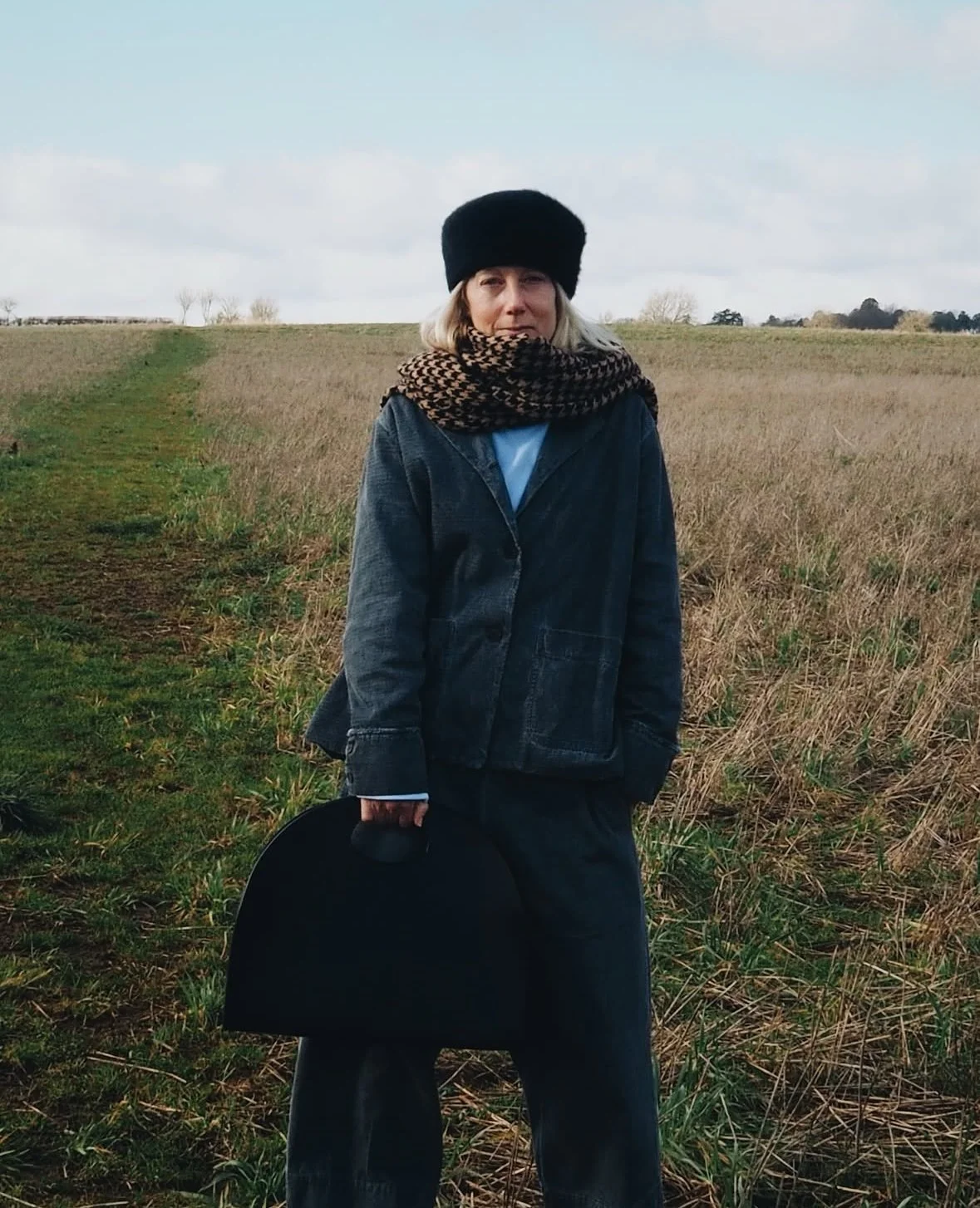 Lady in a field holding a black large statement tote bag with cut out handle