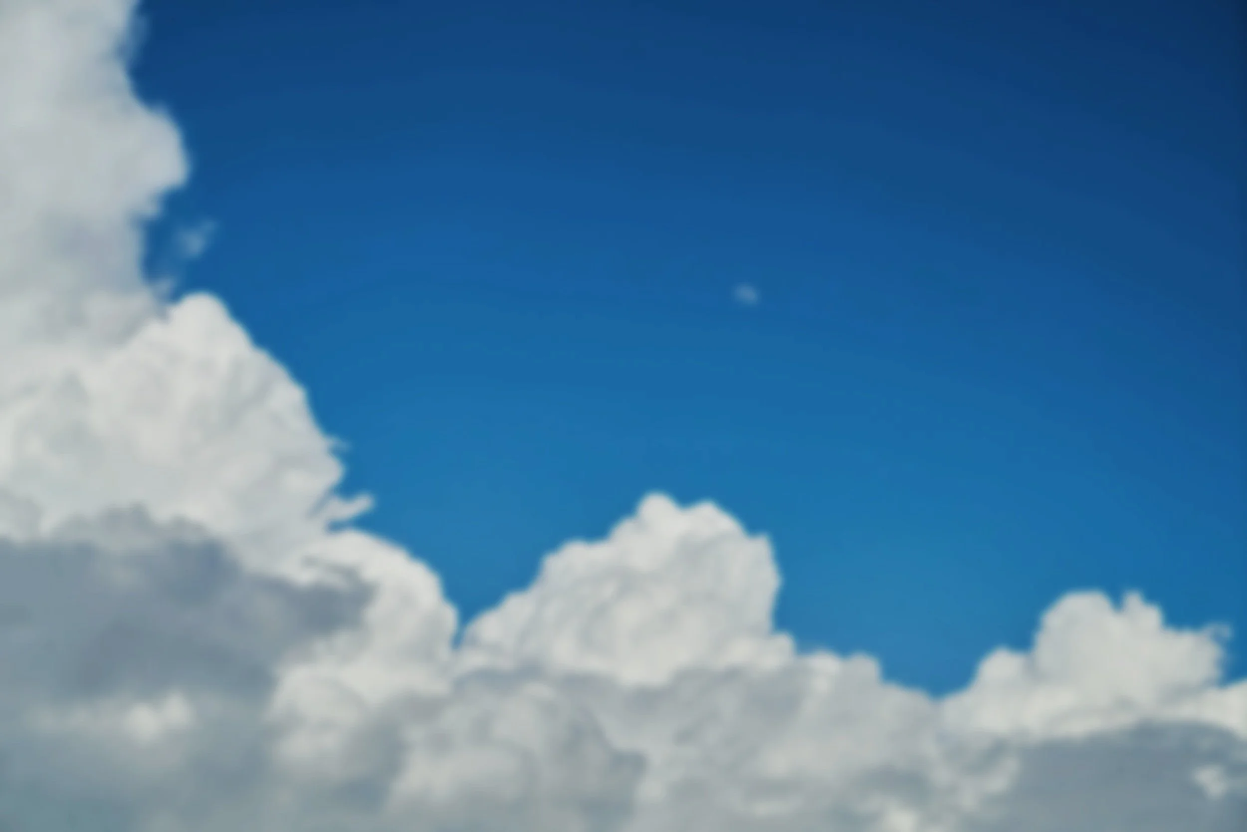 Blue sky with large white clouds and a visible moon.