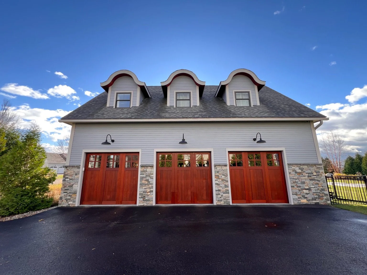 Freshly painted exterior home with gray siding, white trim, and stained wood garage doors in Vermont.