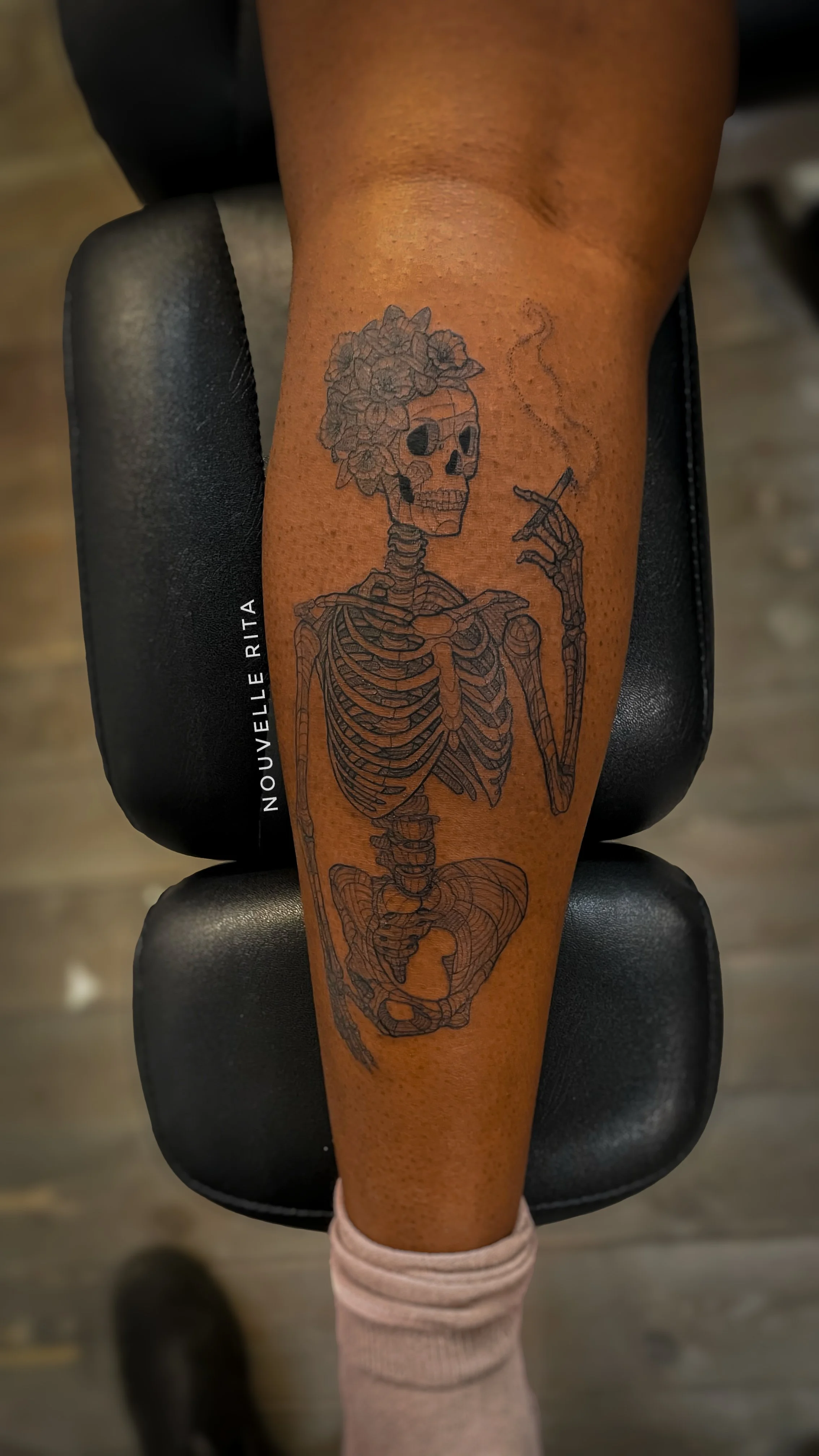 A skeleton smoking a cigarette, with daffodils on their head.